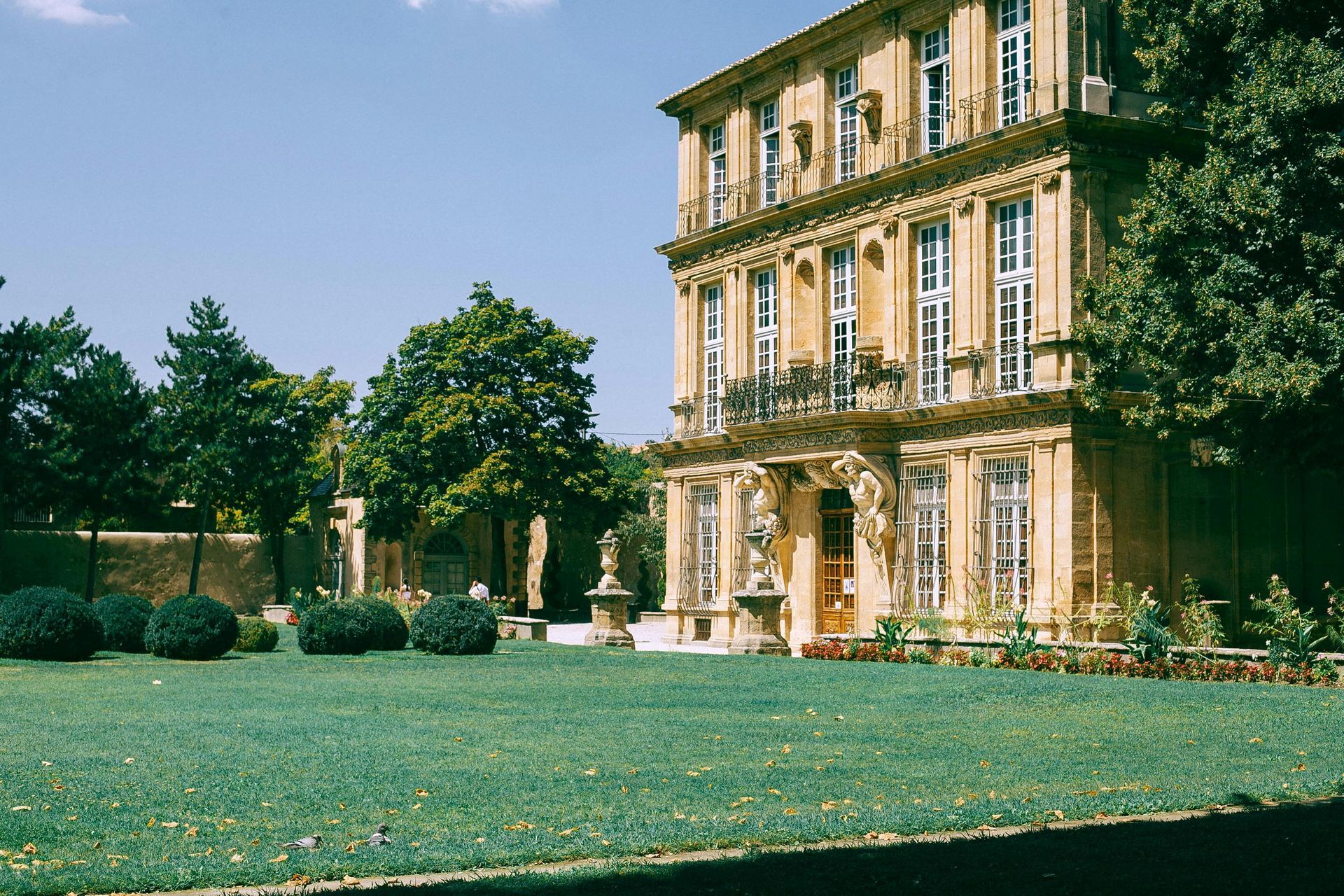 A large building with a lush green lawn in front of it in Aix-en-Provence.