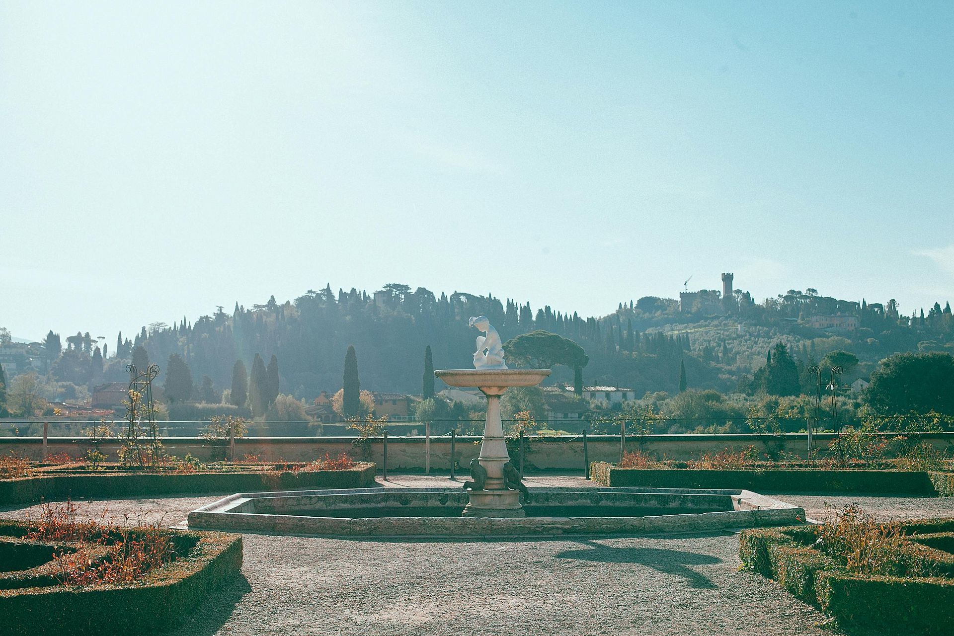 A fountain in a park with a mountain in the background in Florence, Italy.