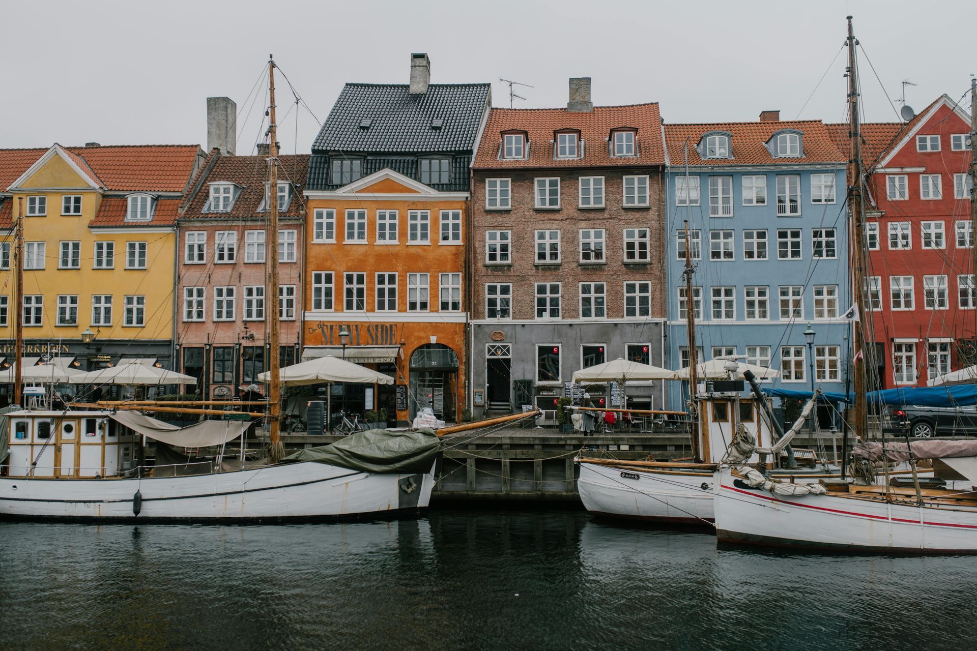 A row of buildings next to a body of water with boats docked in front of them in Denmark.