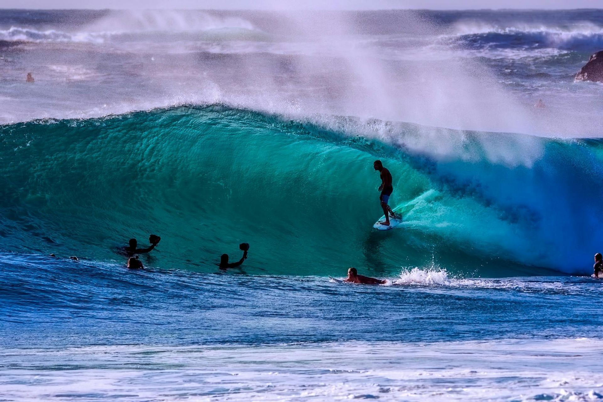 A group of surfers are riding a wave in the ocean in Australia.