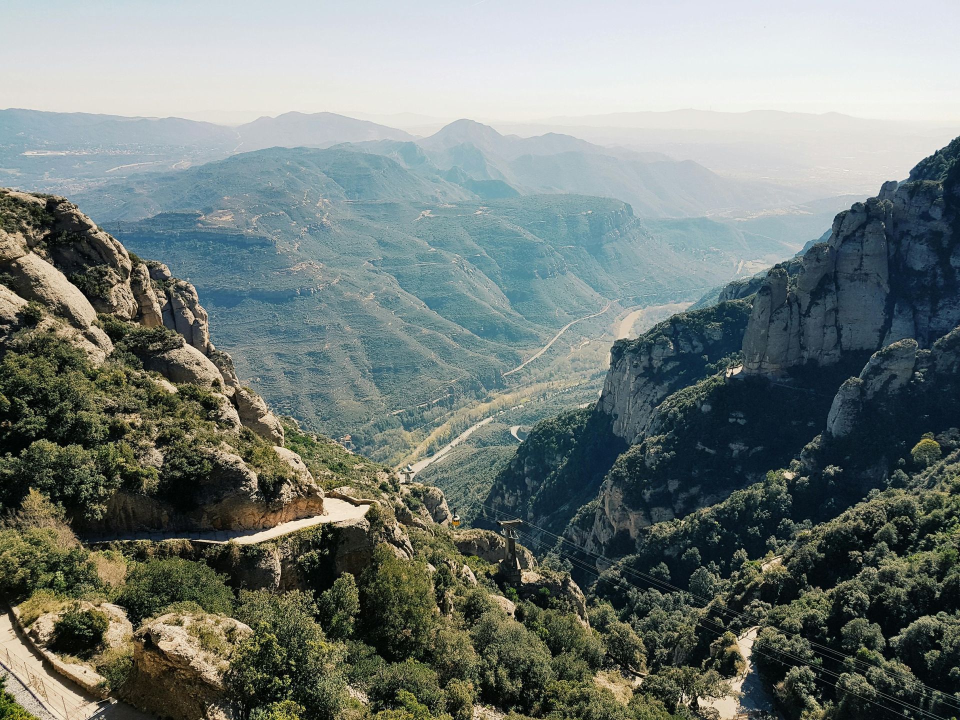 An aerial view of a valley surrounded by the mountain Montserrat and trees in Spain.