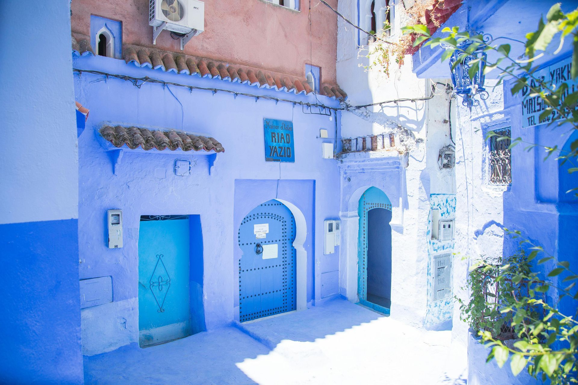 A narrow alleyway between two blue buildings in Morocco.