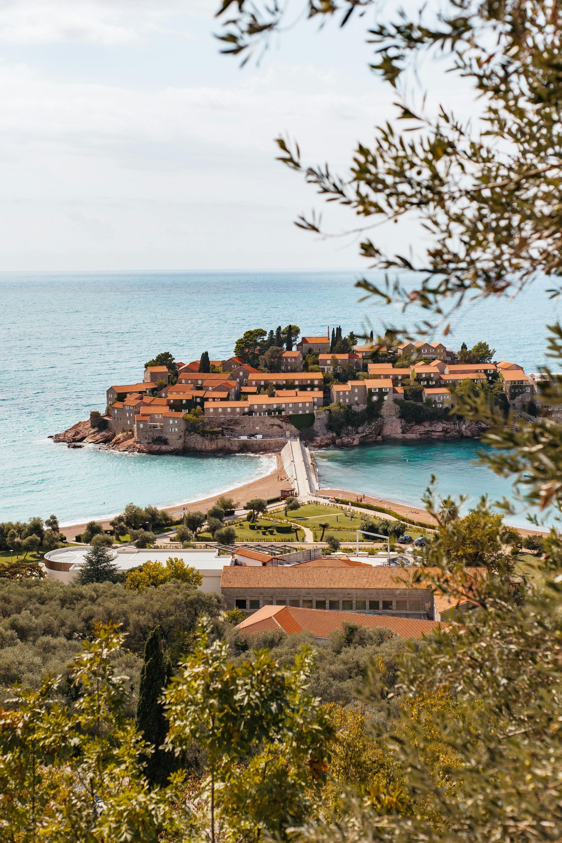 An aerial view of Sveti Stefan in the middle of the ocean surrounded by trees in Montenegro.