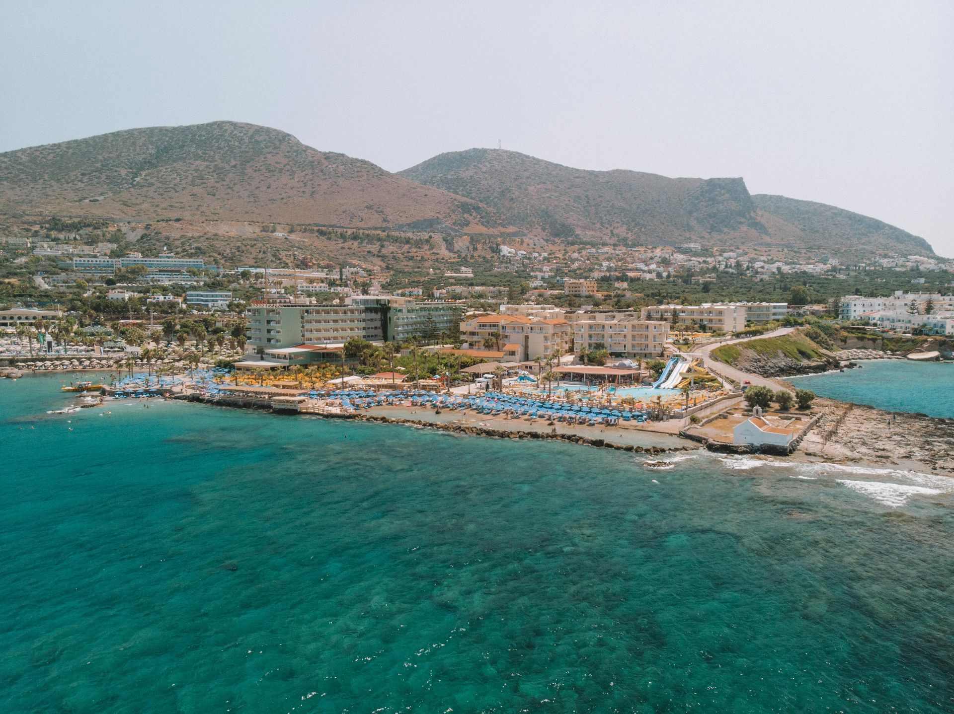 An aerial view of a beach with mountains in the background in Crete, Greece.