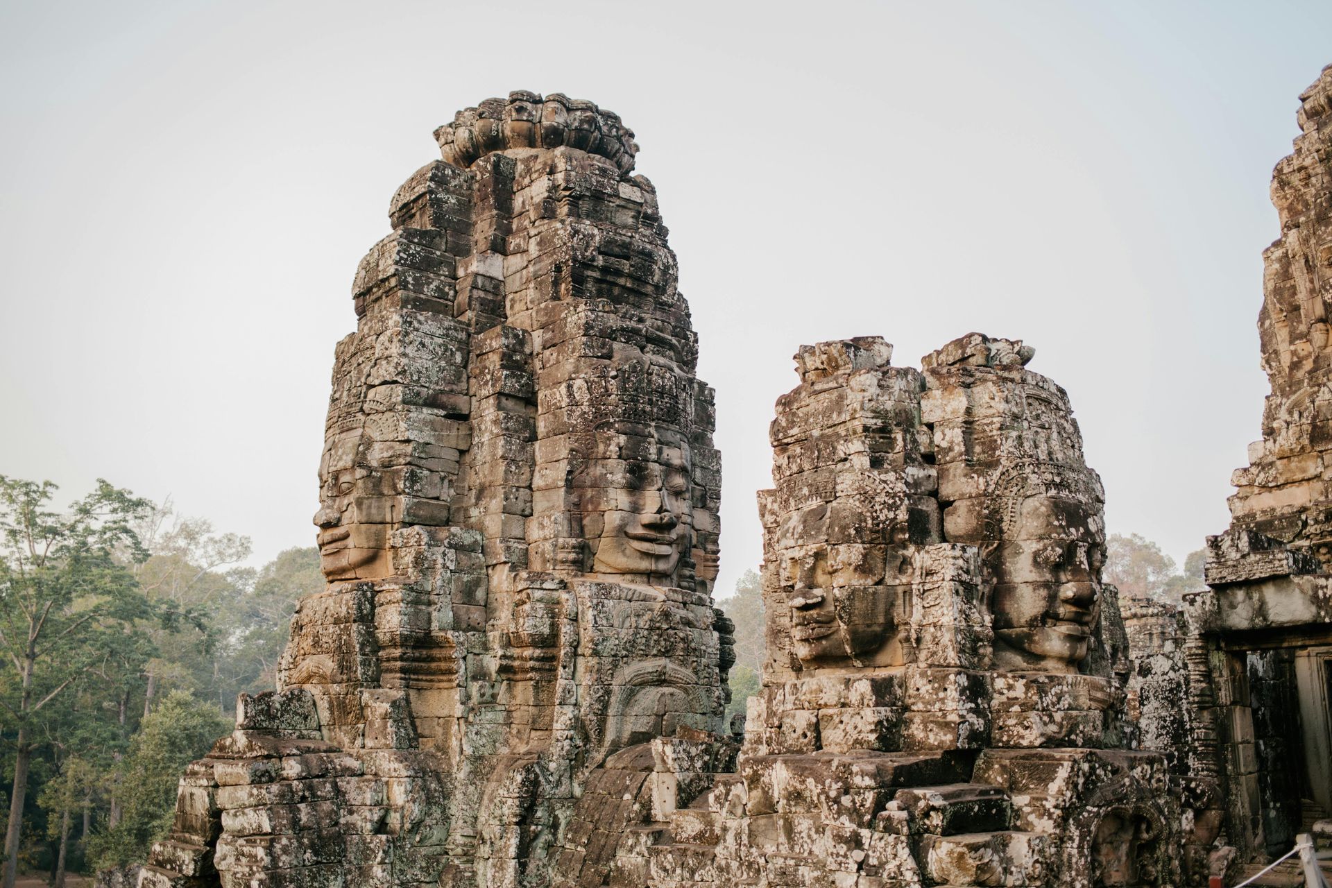 A group of stone statues with faces carved into them at the Bayon Temple in Cambodia.