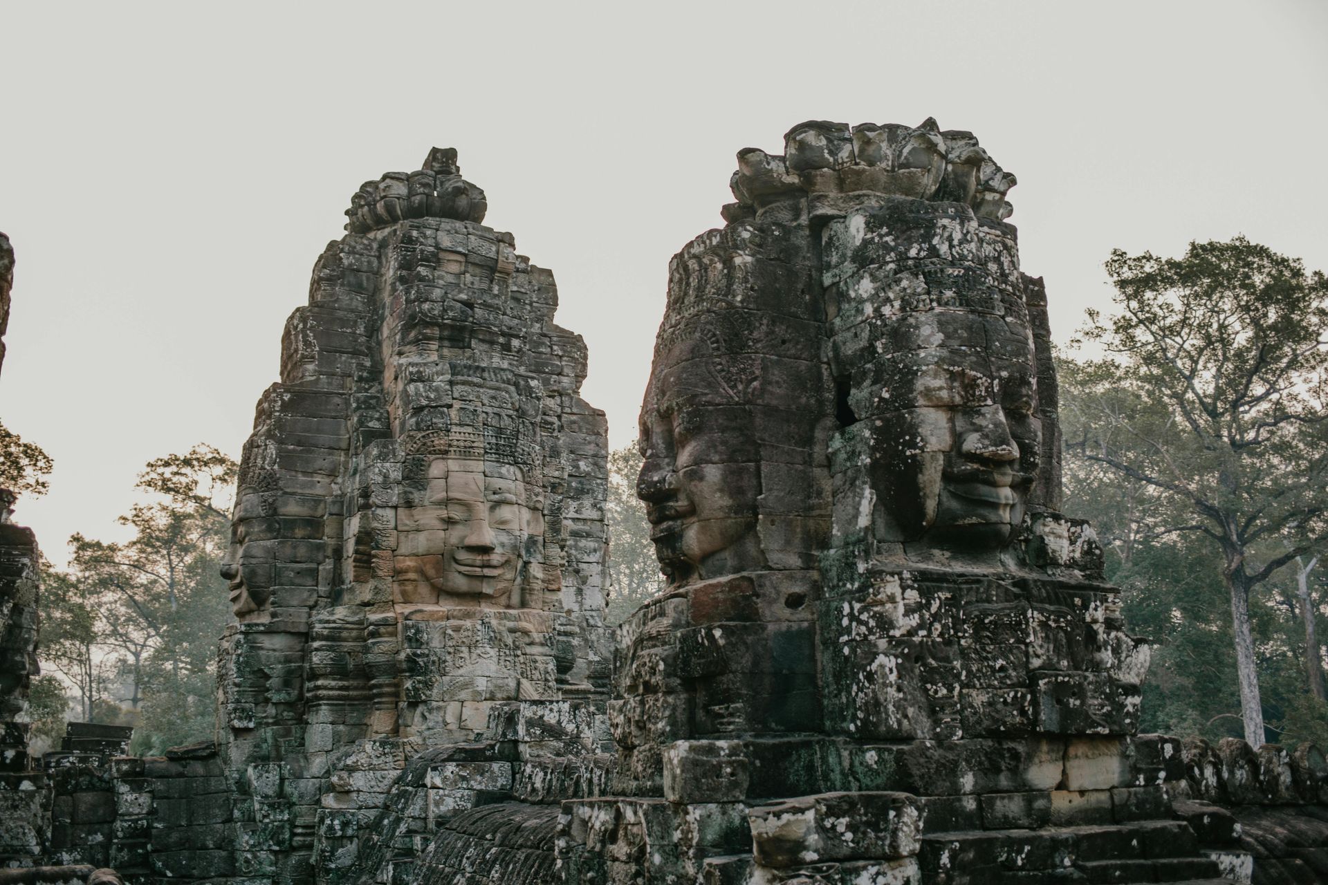 A group of stone statues with faces carved into them in Cambodia.