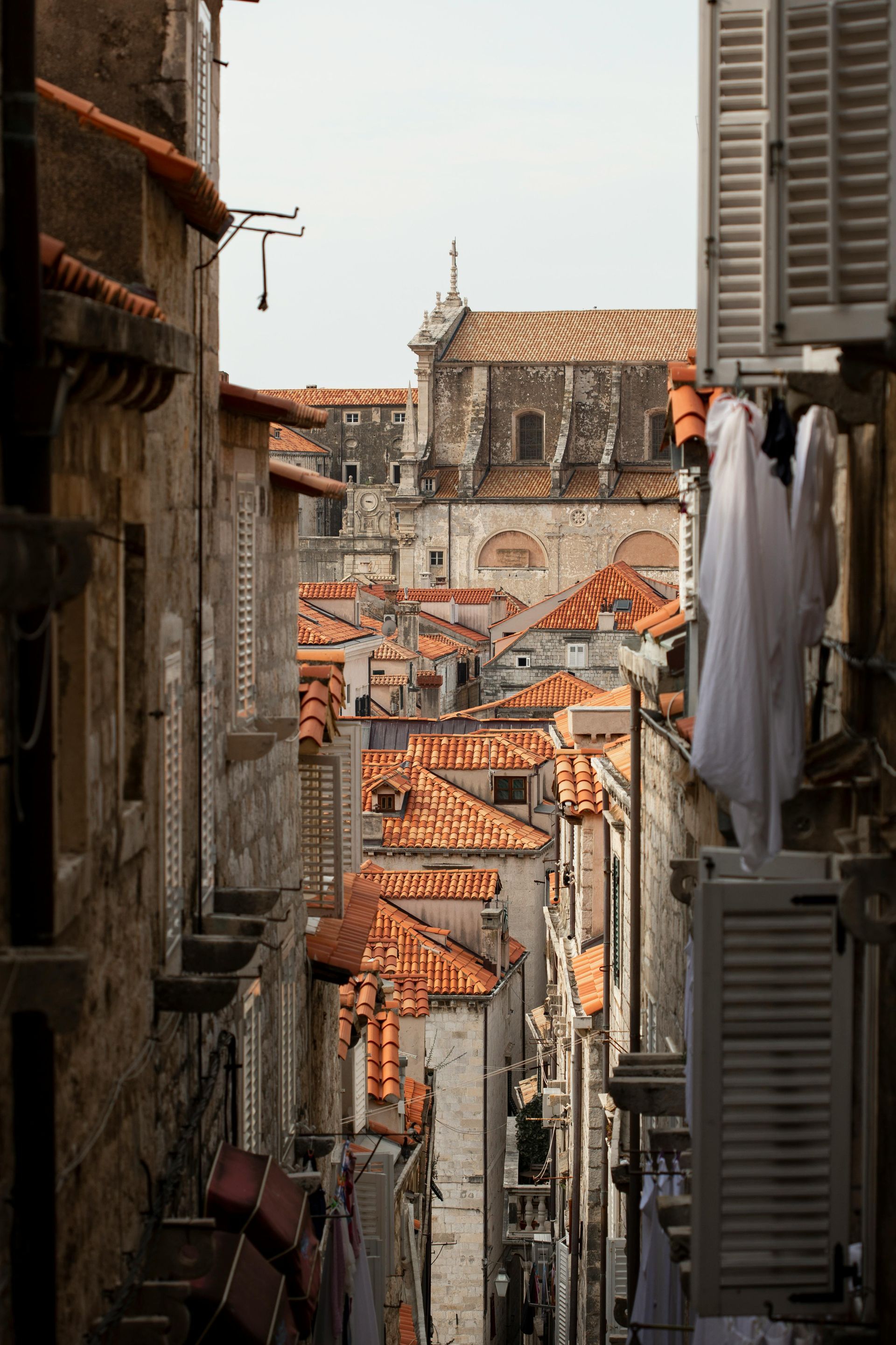 A narrow alleyway between two buildings with a church in the background in Croatia. 