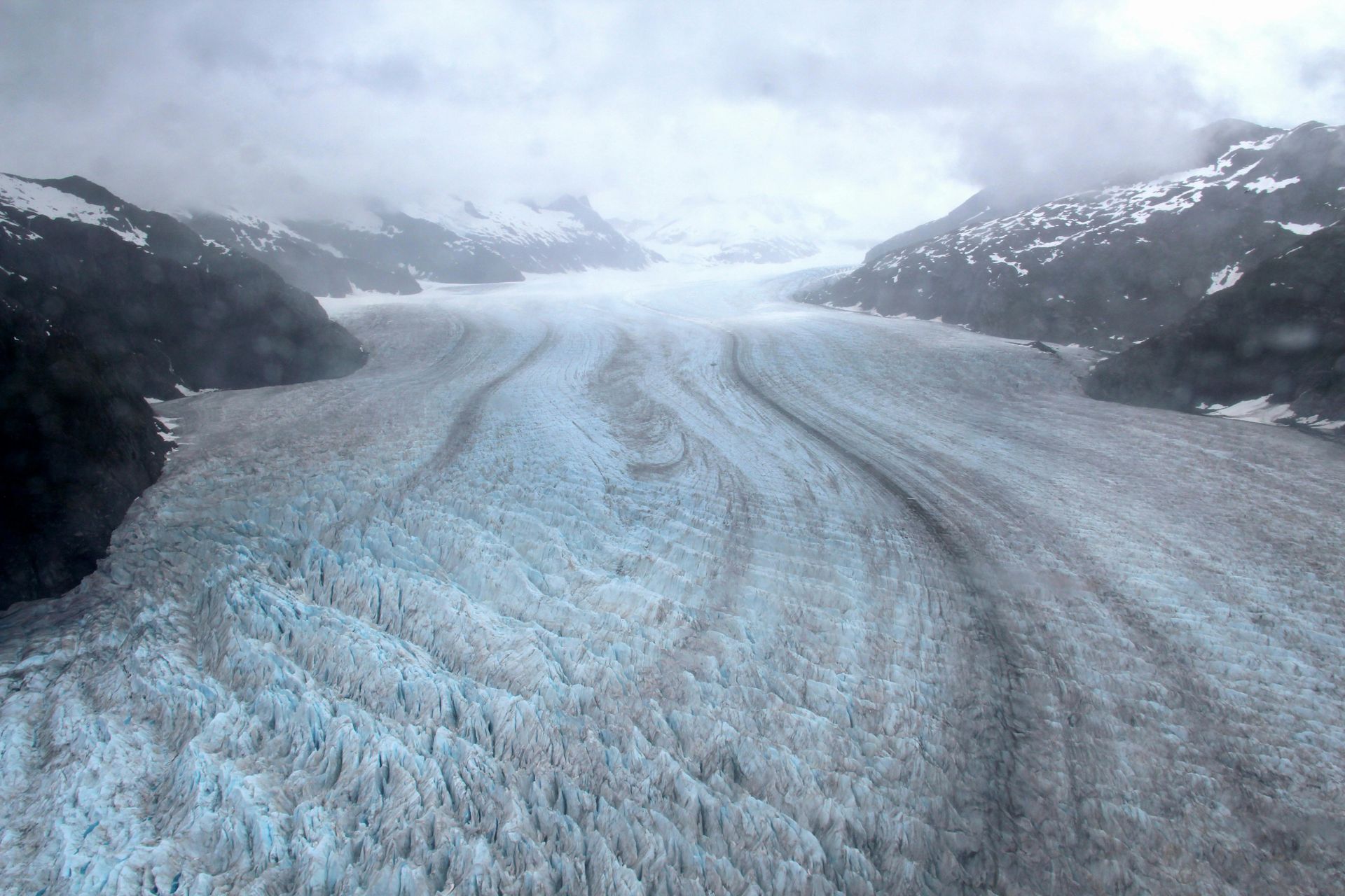 A large body of water surrounded by snow and mountains in Alaska. 