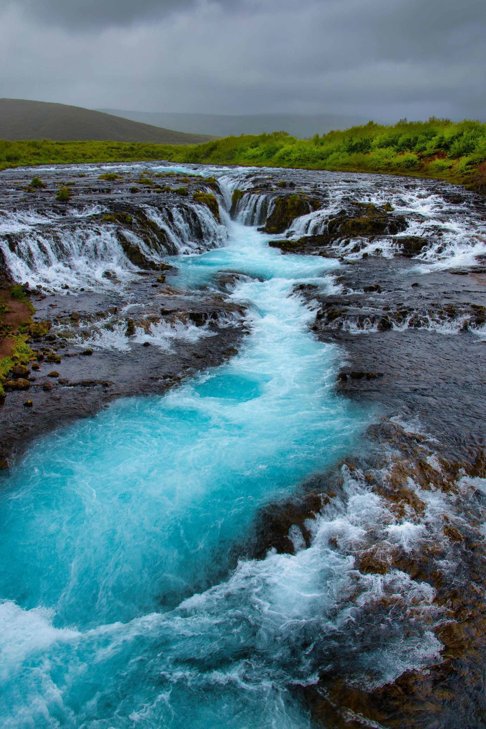 A river flowing through a rocky area with a waterfall in the background in Finland.