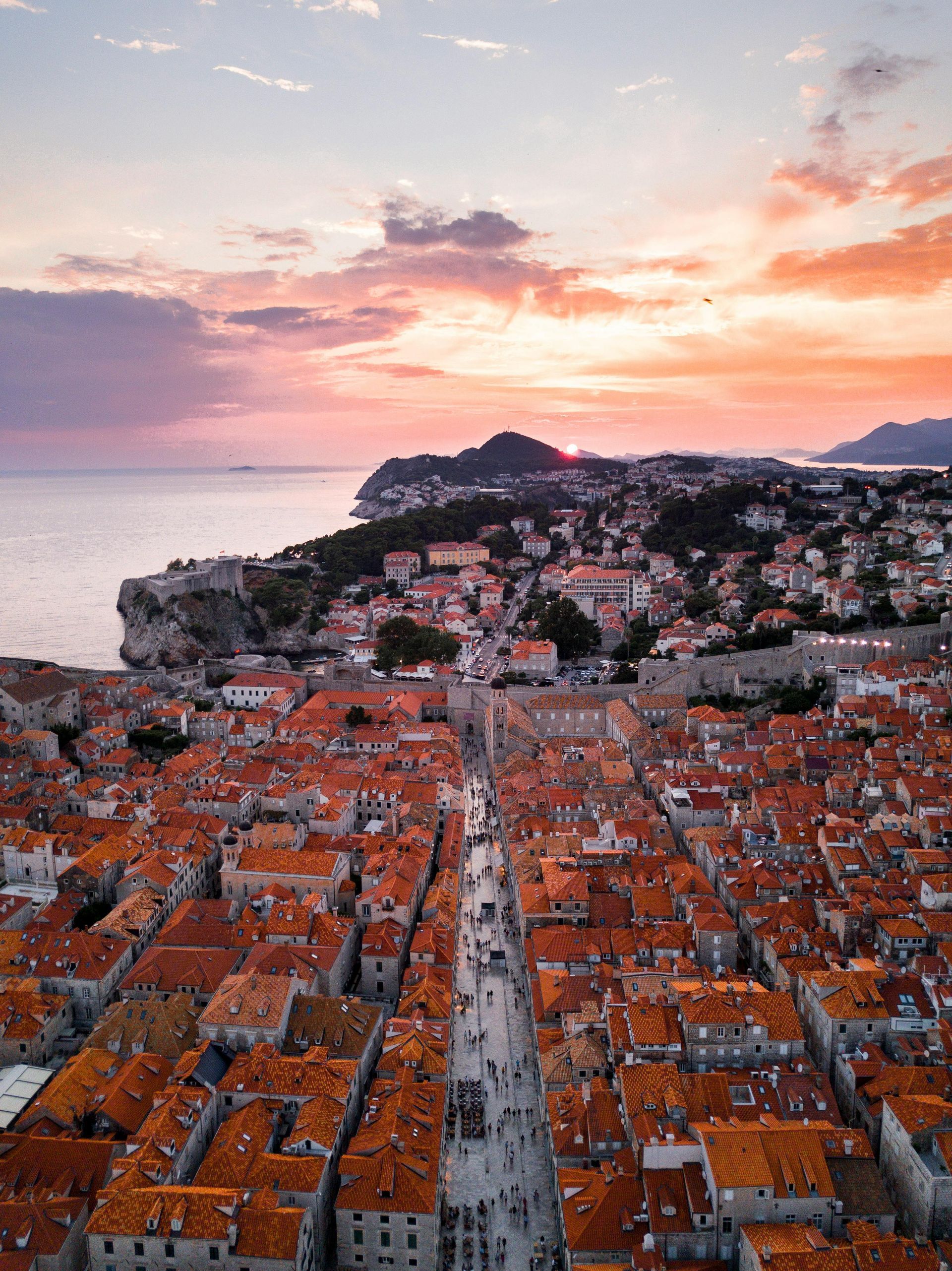 An aerial view of a city with red tiled roofs at sunset in Dubrovnik, Croatia. 