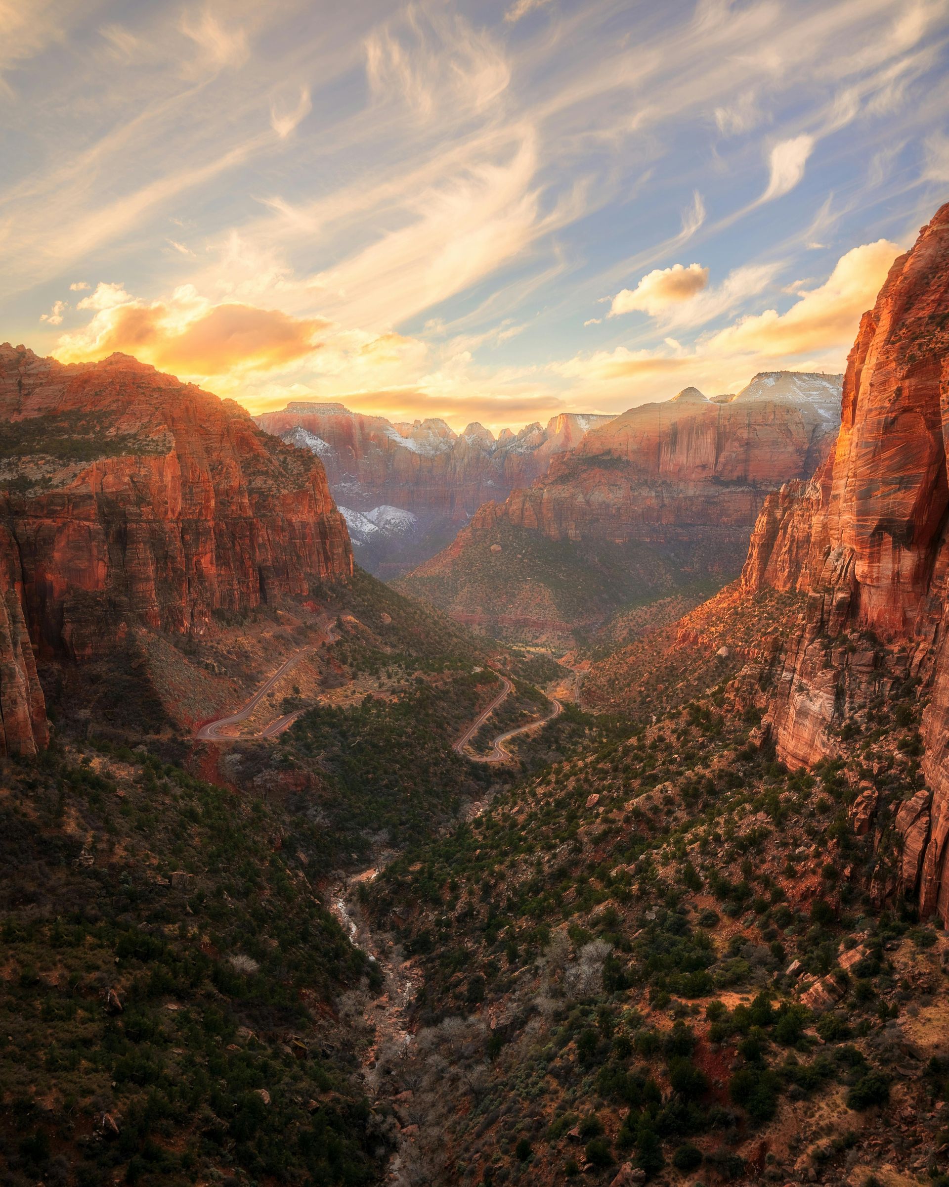 An aerial view of a canyon at sunset with mountains in the background at Zion National Park.