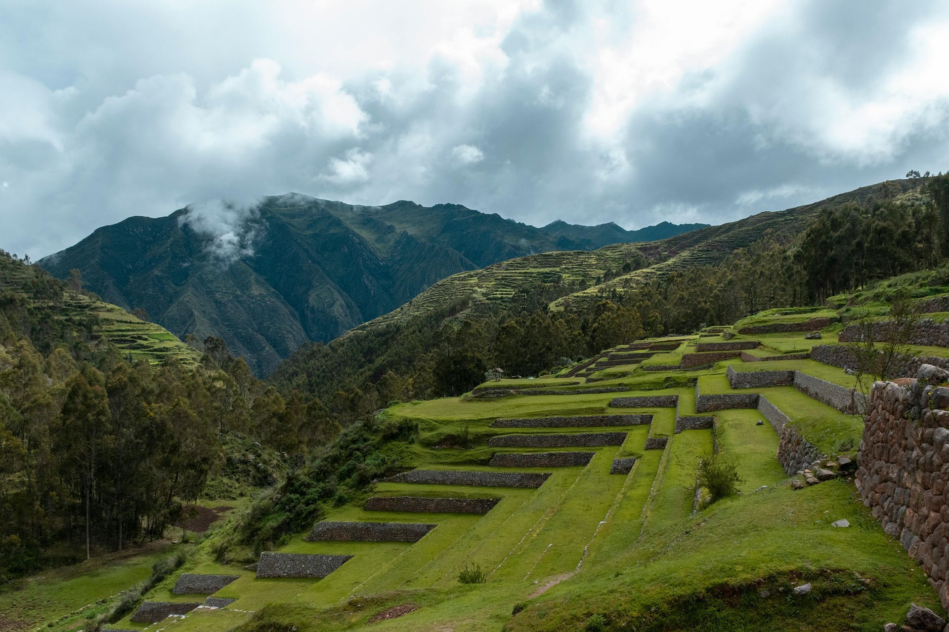 A lush green hillside with mountains in the background in the sacred valley in Peru.