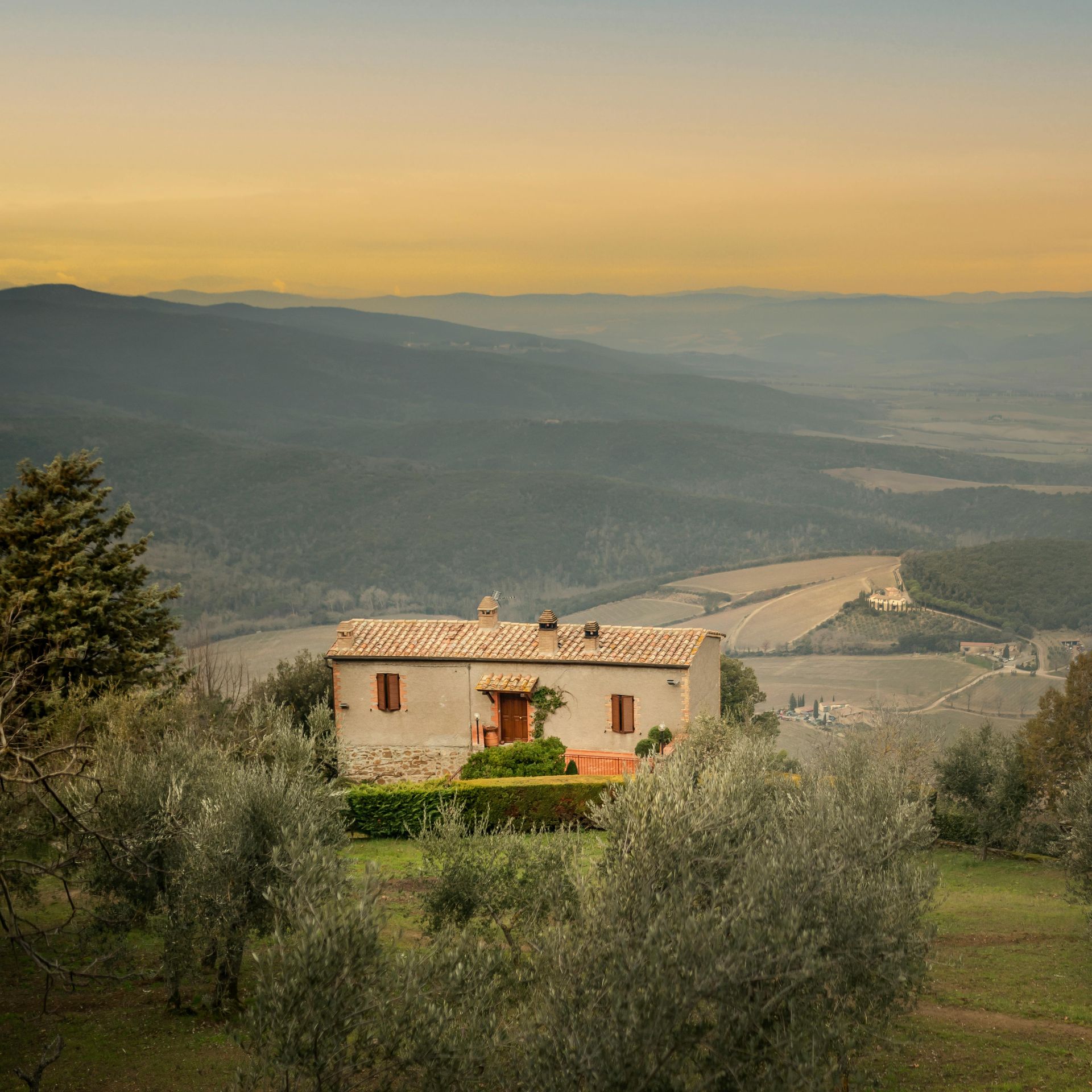 A small house is sitting on top of a hill overlooking a valley in Tuscany, Italy.