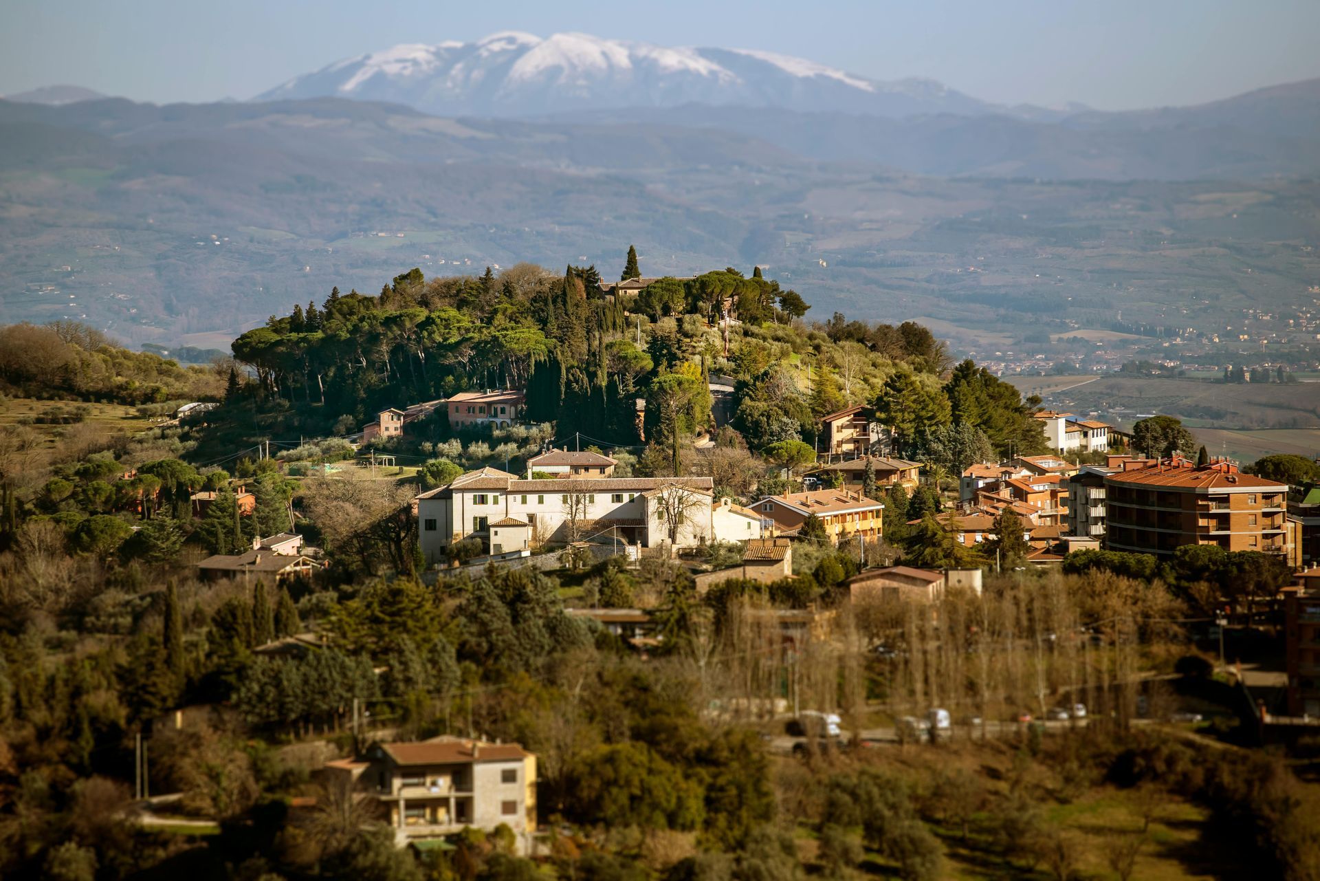 A small town on top of a hill with mountains in the background in Tuscany, Italy.