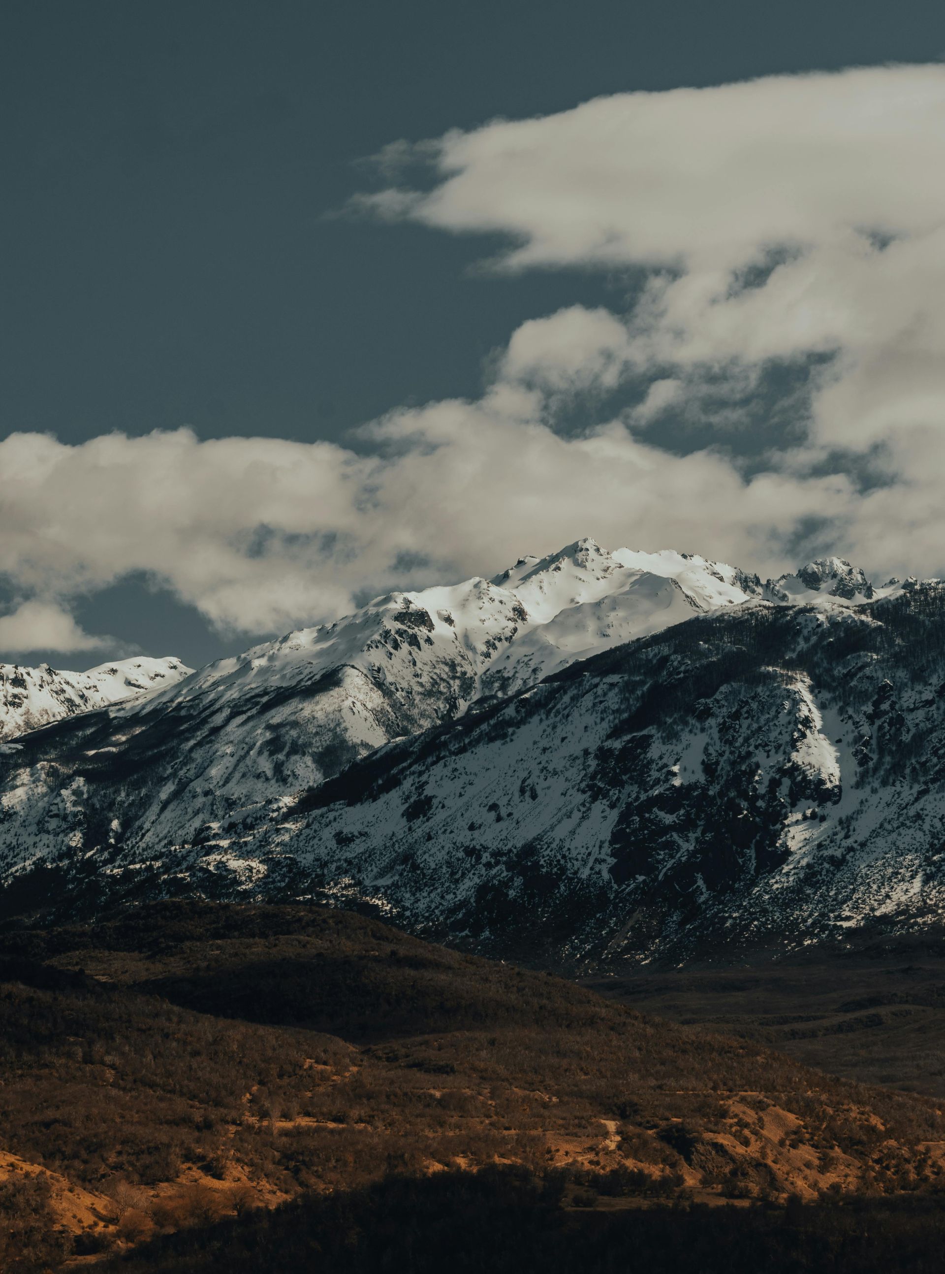 A mountain covered in snow with a cloudy sky in the background in Alaska. 