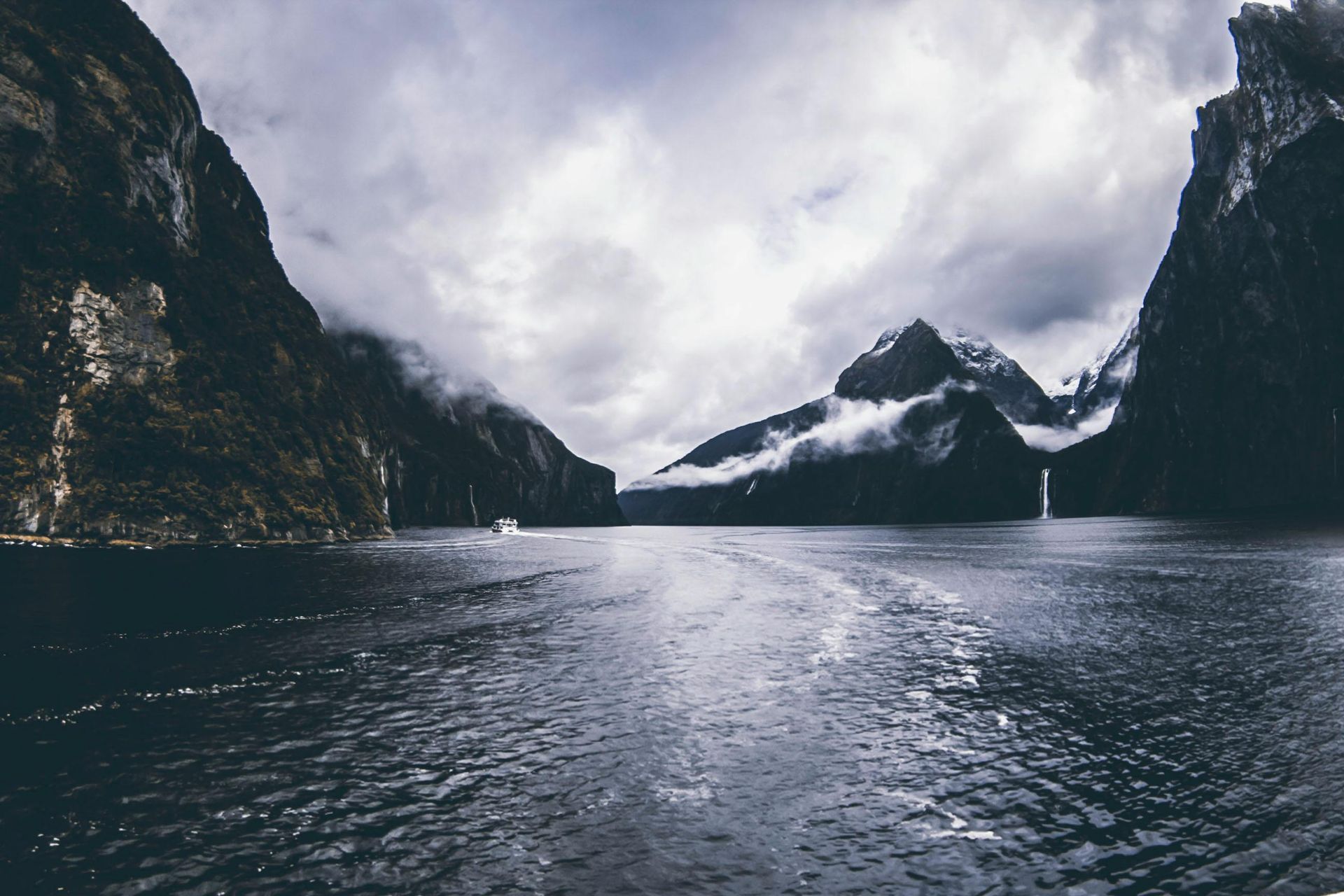 A boat is floating on a lake surrounded by mountains in New Zeland.