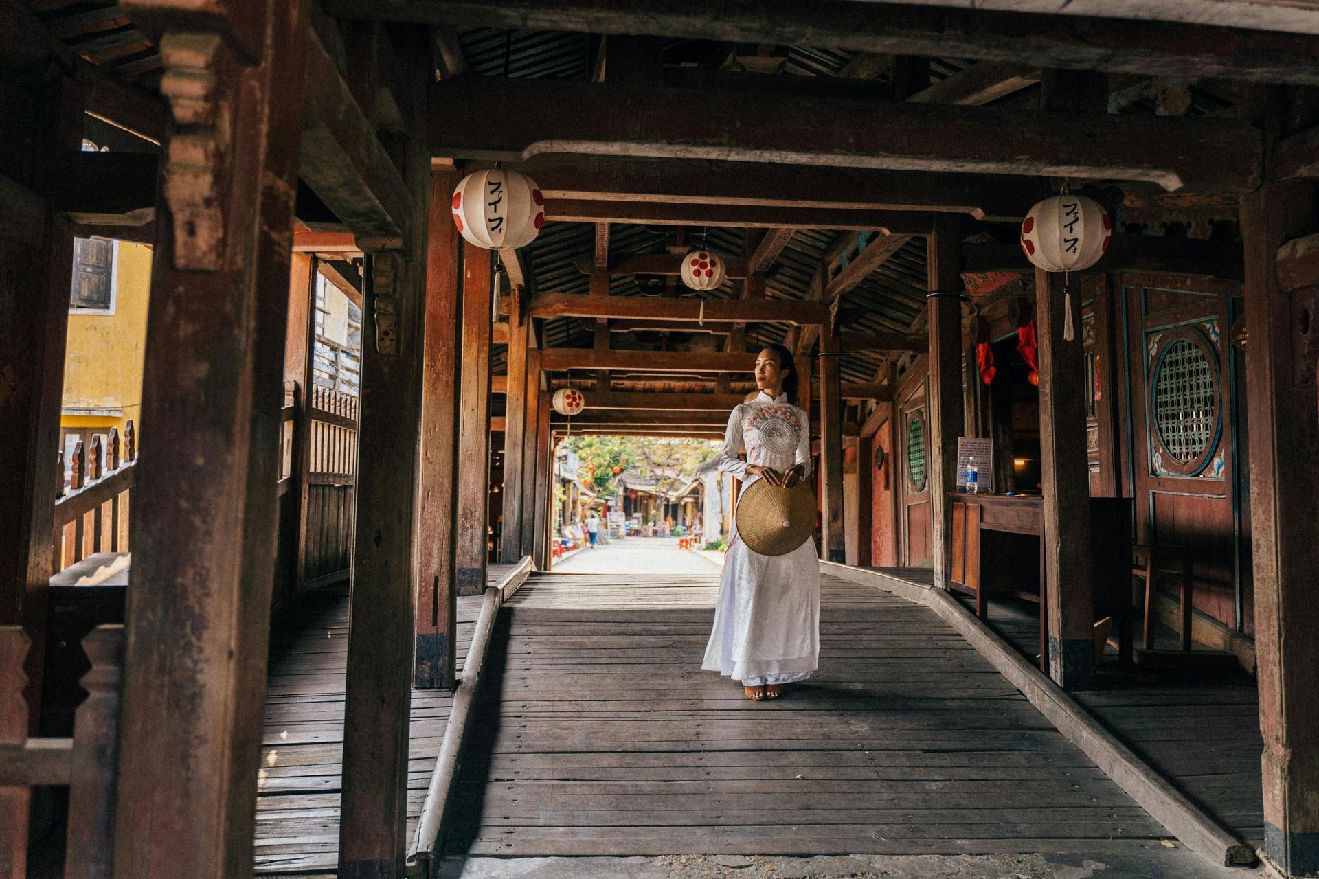 A woman is walking across a the Chùa Cầu Phố cổ Hội An Bridge in Hội An, Vietnam.