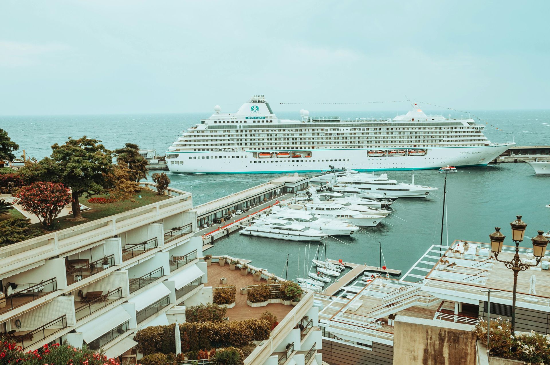 A large cruise ship is docked in Port Hercule surrounded by boats in Monaco.