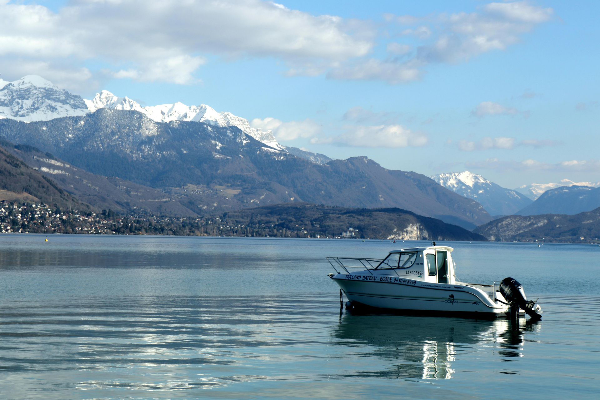 A boat is floating on lake Annecy with mountains in the background in Annecy, France.