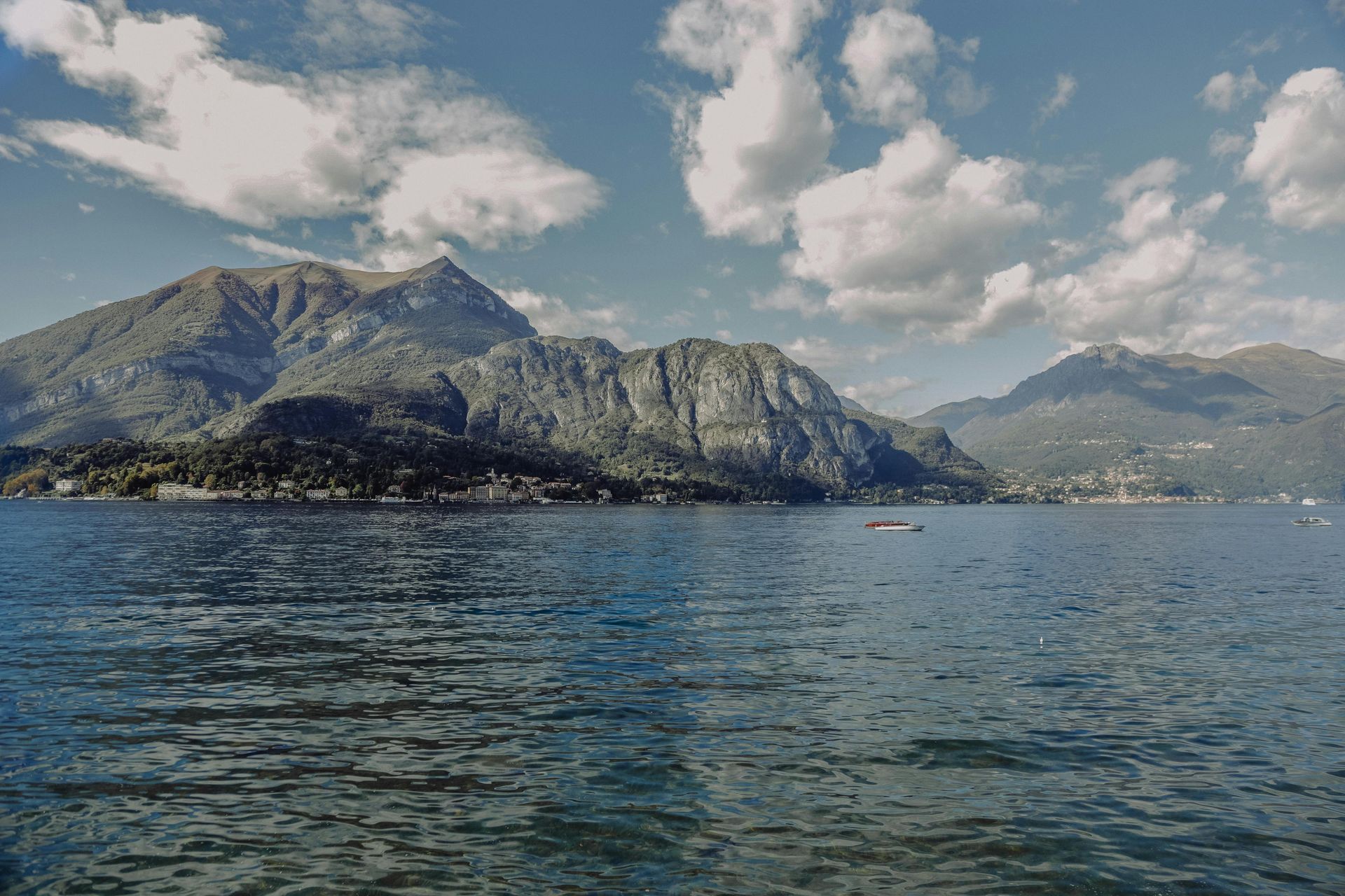 Lake Como with mountains in the background and a boat in the water in Italy.