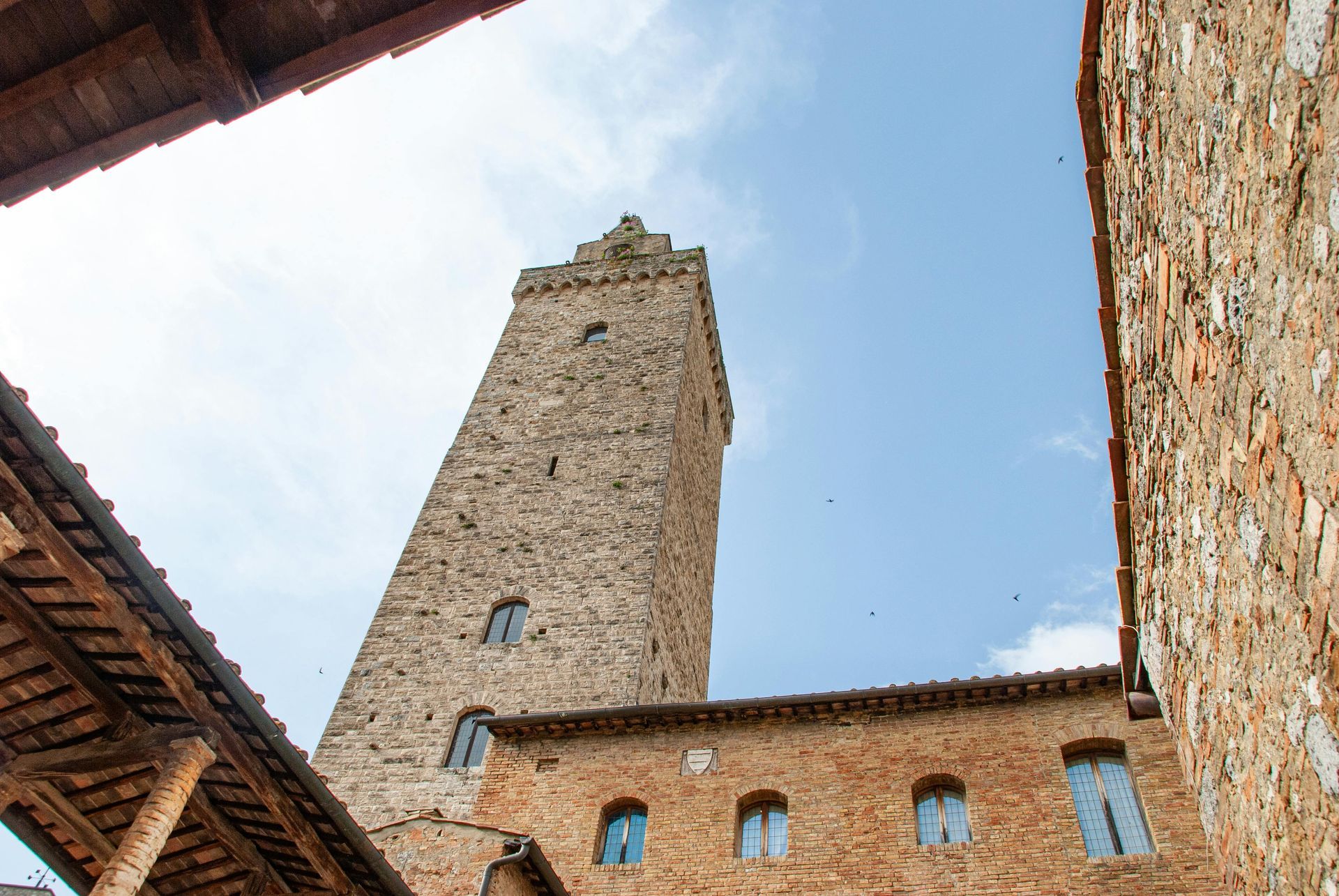 A brick building with a tower in the middle of it in Tuscany, Italy.