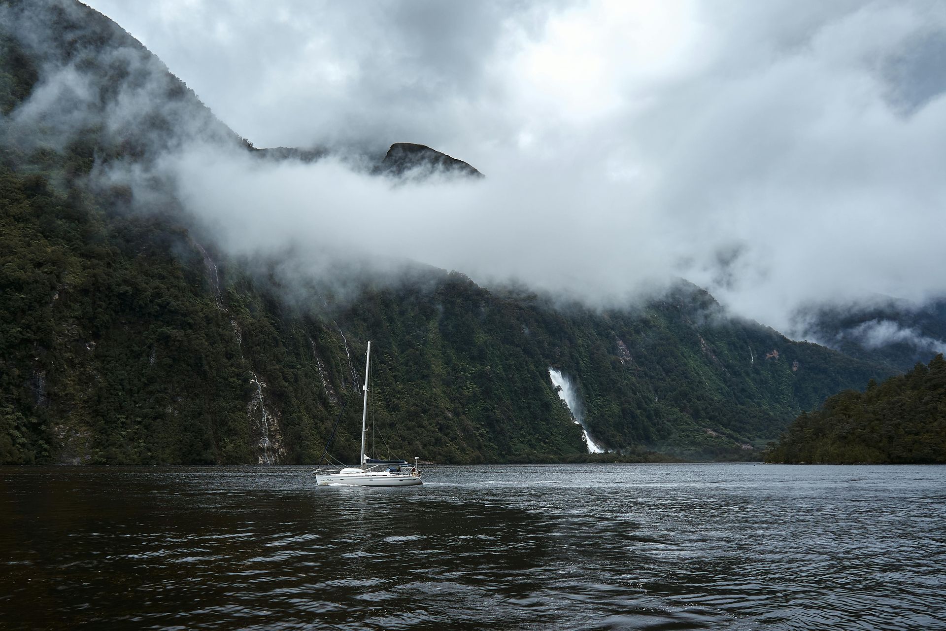 A boat is floating on a lake with mountains in the background in New Zeland.