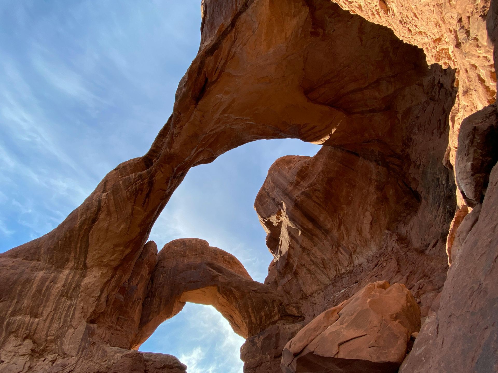 Looking up at a rock formation with a blue sky in the background at Arches National Park in Utah.