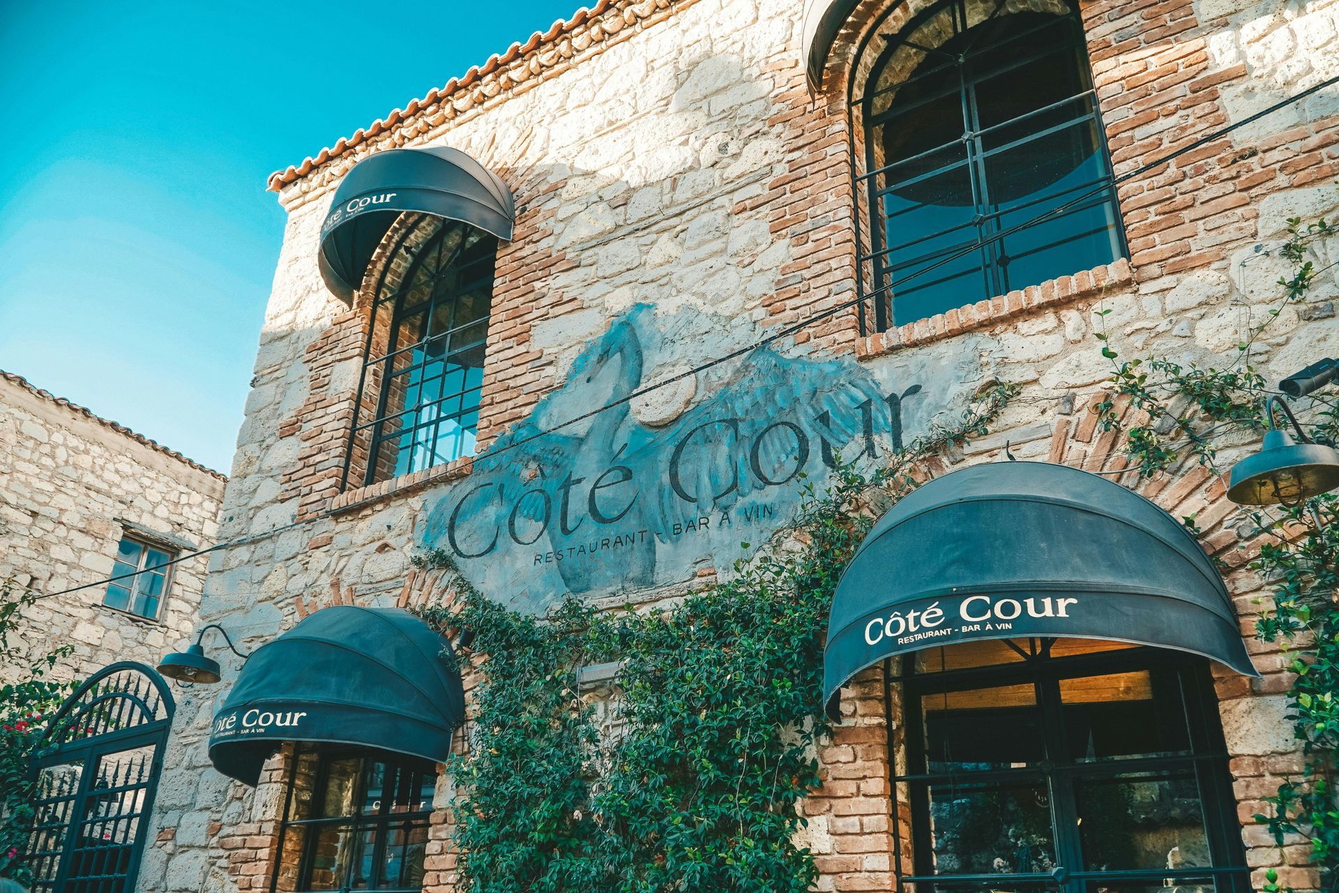 A brick building with a sign that says cafe cour on it in southern France. 