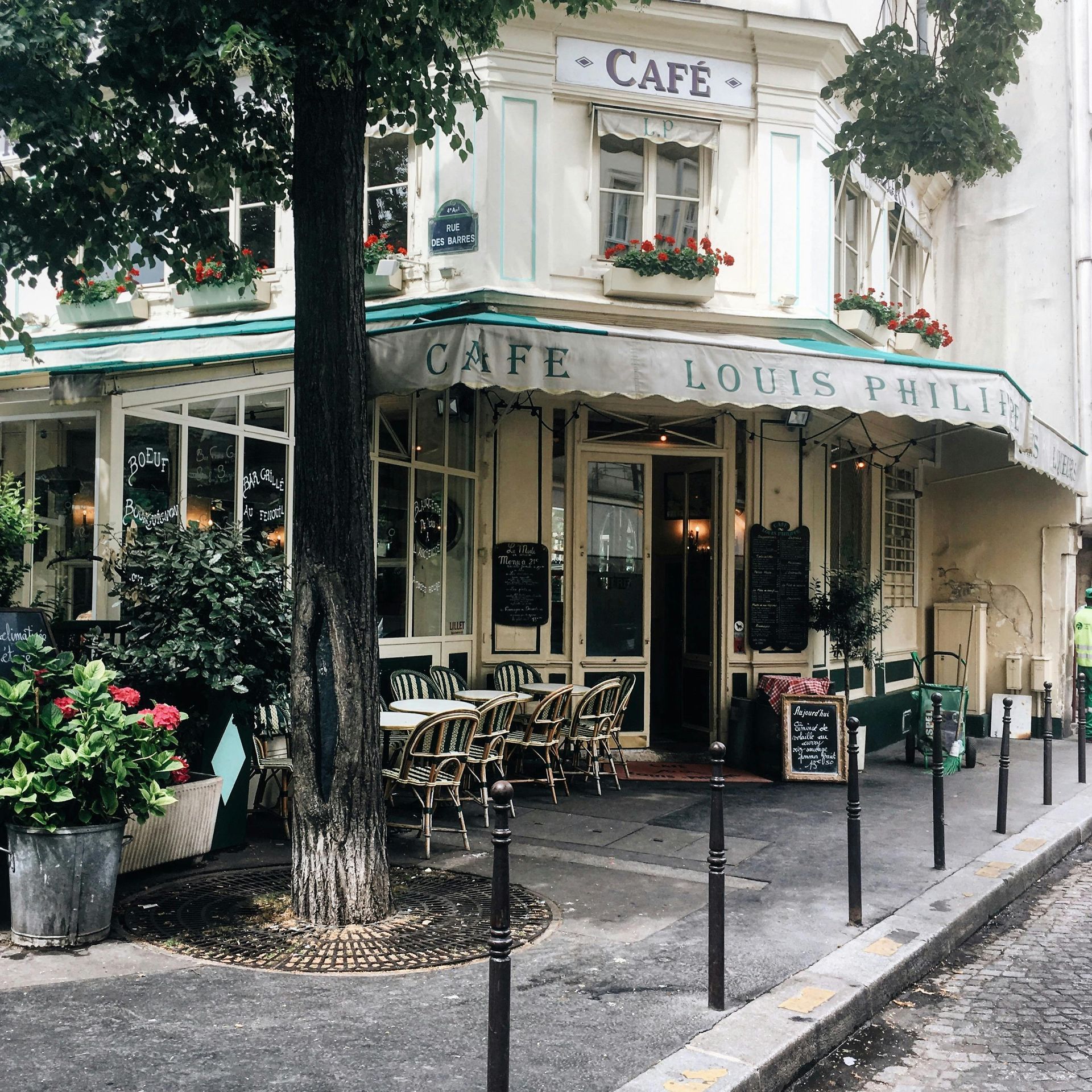 A cafe with tables and chairs in front of it on a street in Paris.