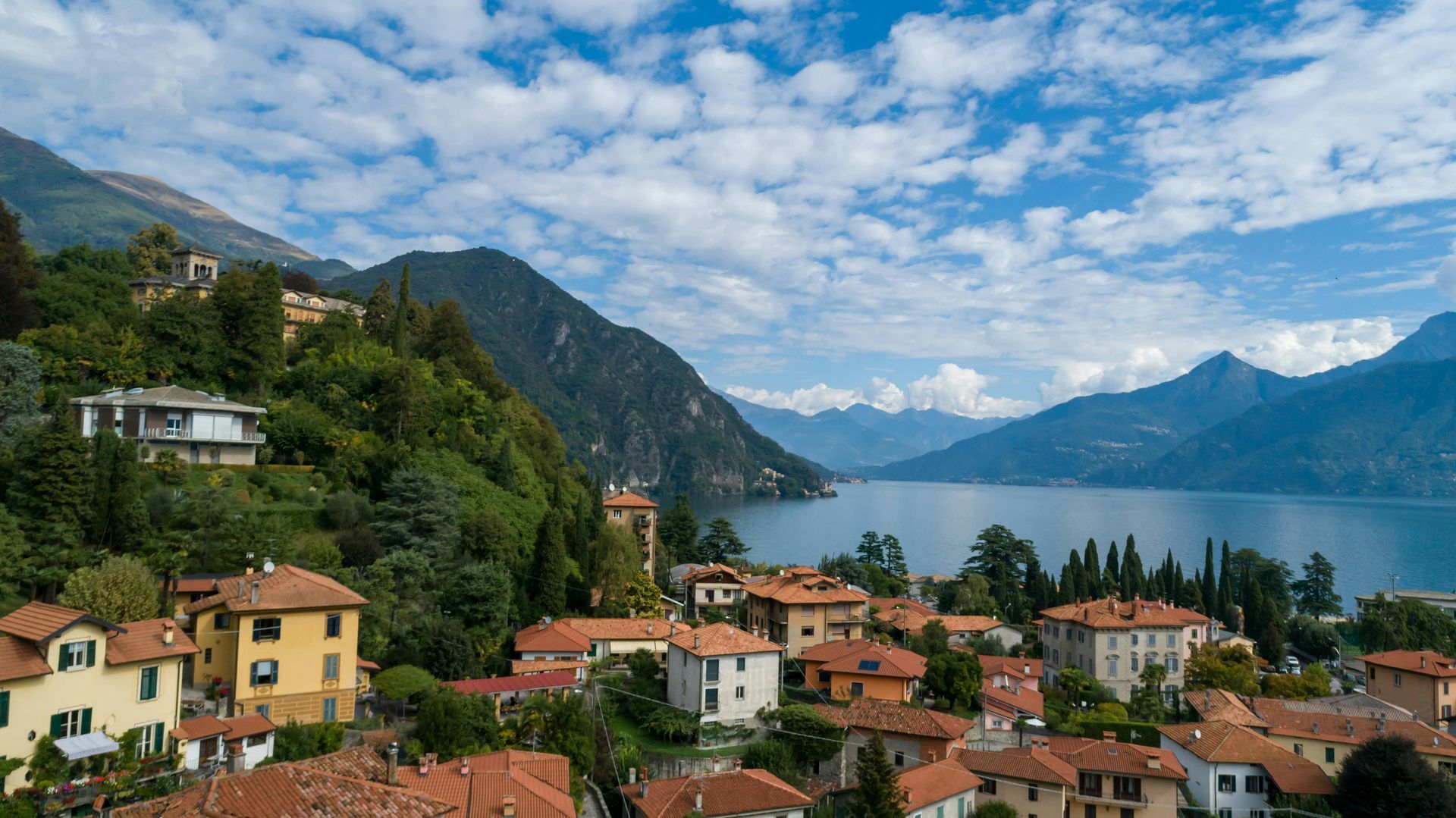 An aerial view of a small town next to Lake Como with mountains in the background in Italy.