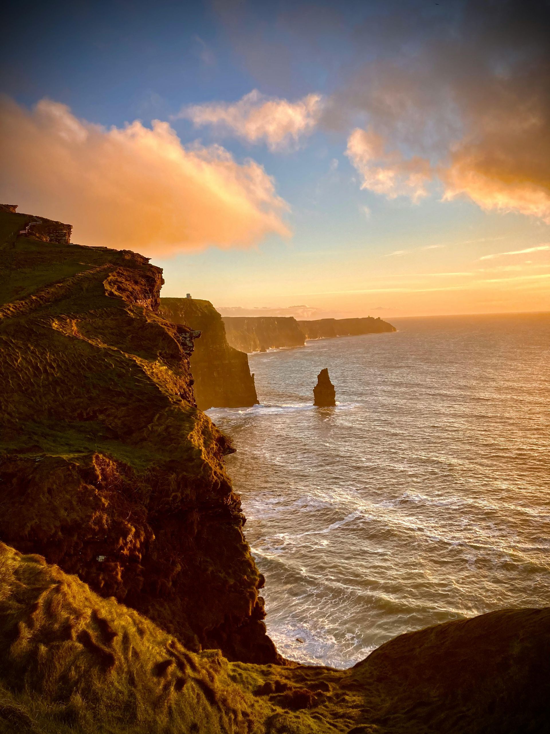 The Cliffs of Moher overlooking a body of water at sunset in Ireland.