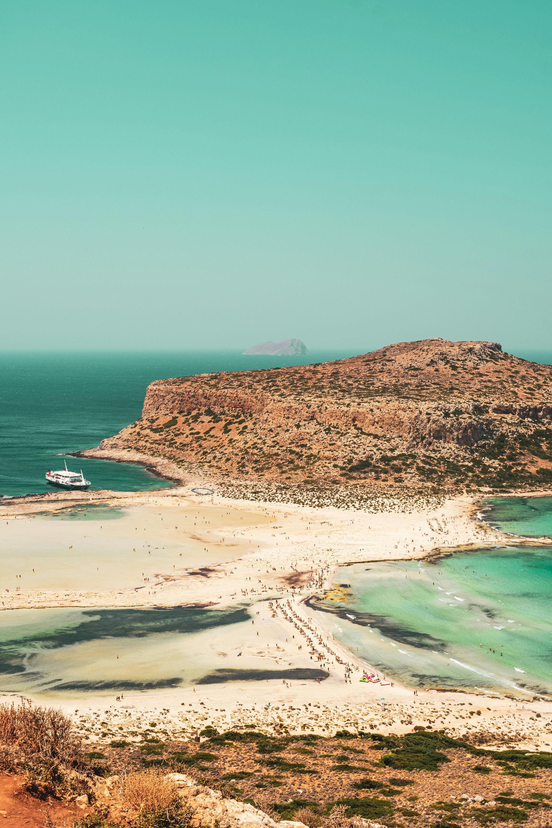 An aerial view of a beach with a boat in the water in Crete, Greece.