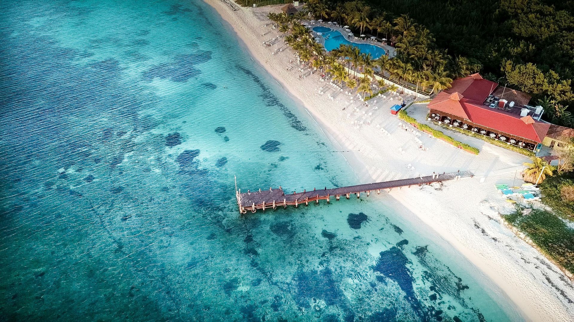 An aerial view of a beach with a pier and a house on Cozumel island in Mexico.