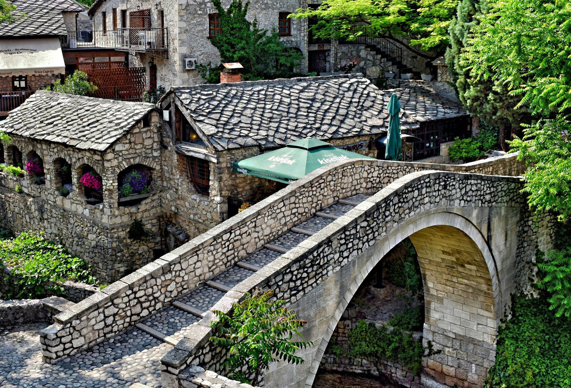 The Old Bridge Mostar over a river in front of a house in Bosnia and Herzegovina.