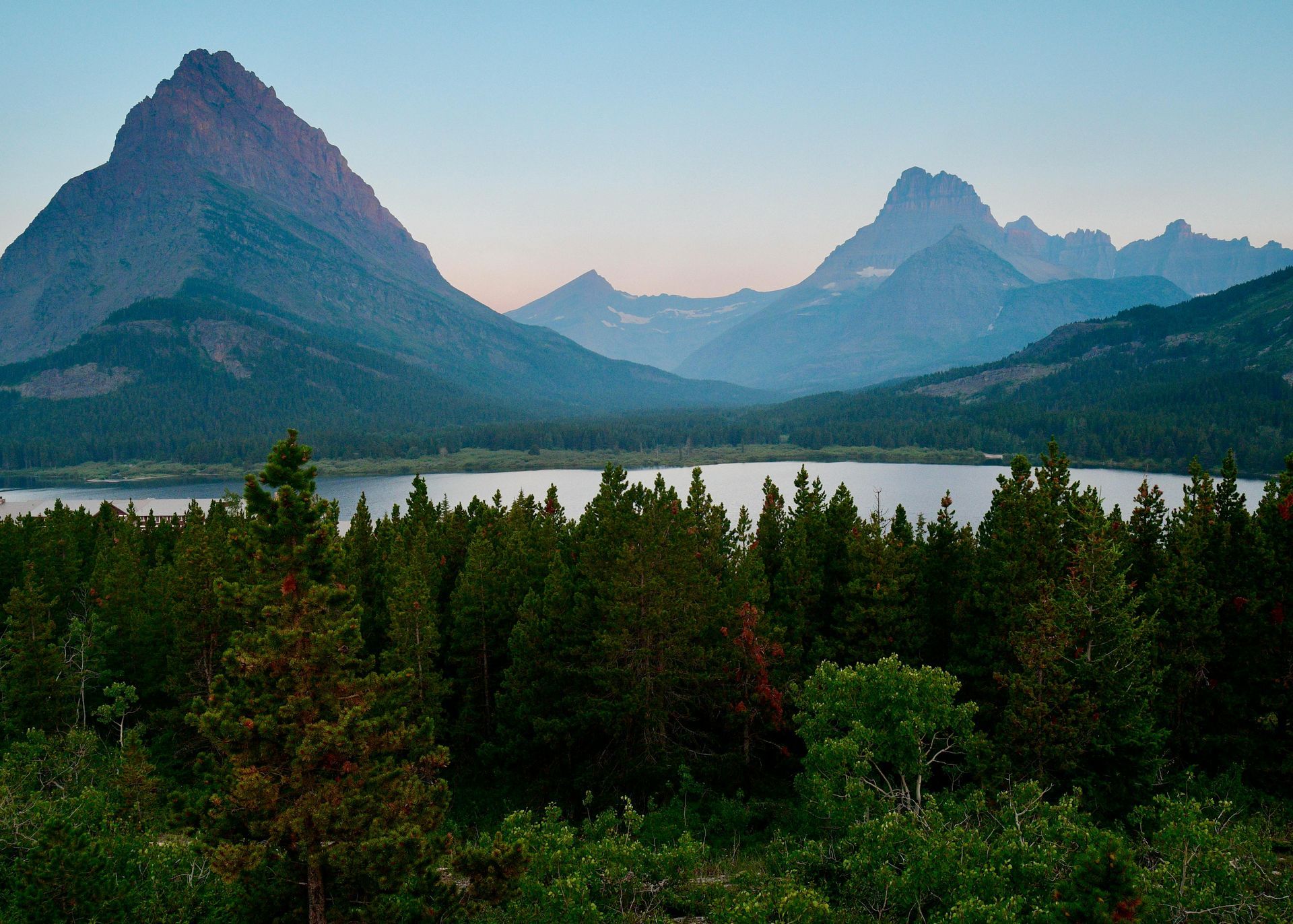 A lake with mountains in the background and trees in the foreground at Glacier National Park in Montana.