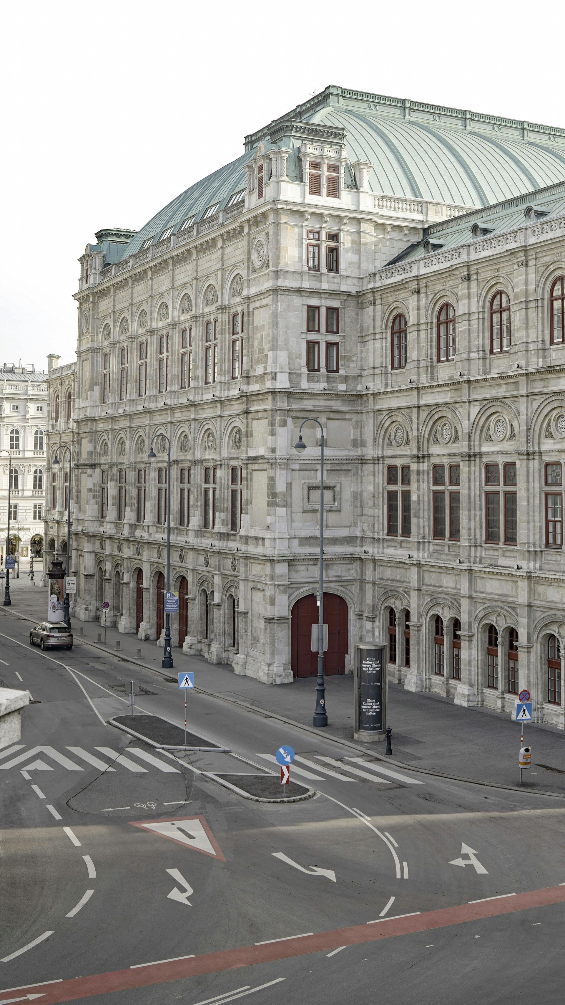 Vienna State Opera Hoouse with a green roof is in the middle of a city street in Vienna, Austria.