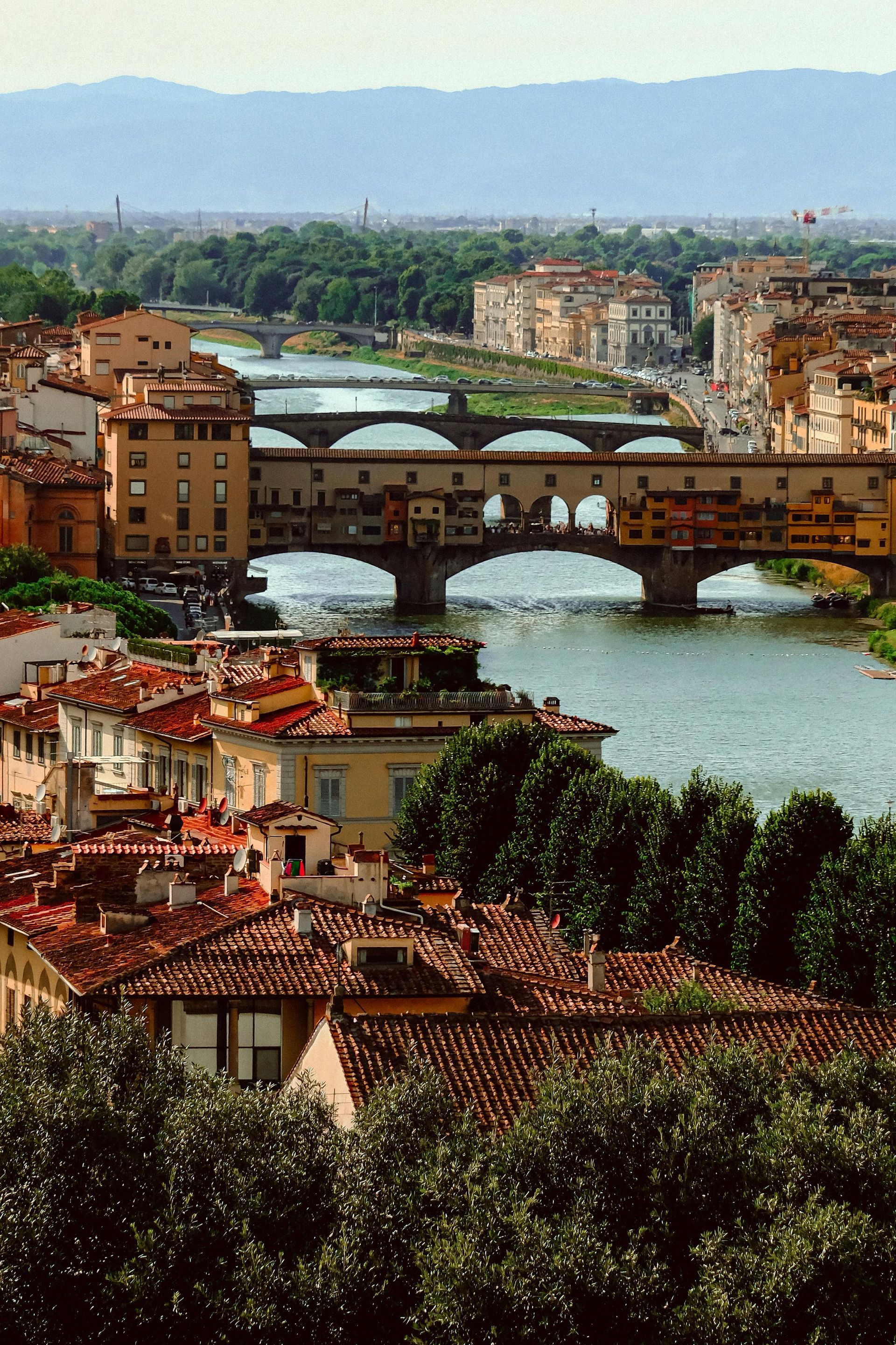 A bridge over a river surrounded by buildings and trees in Florence, Italy.