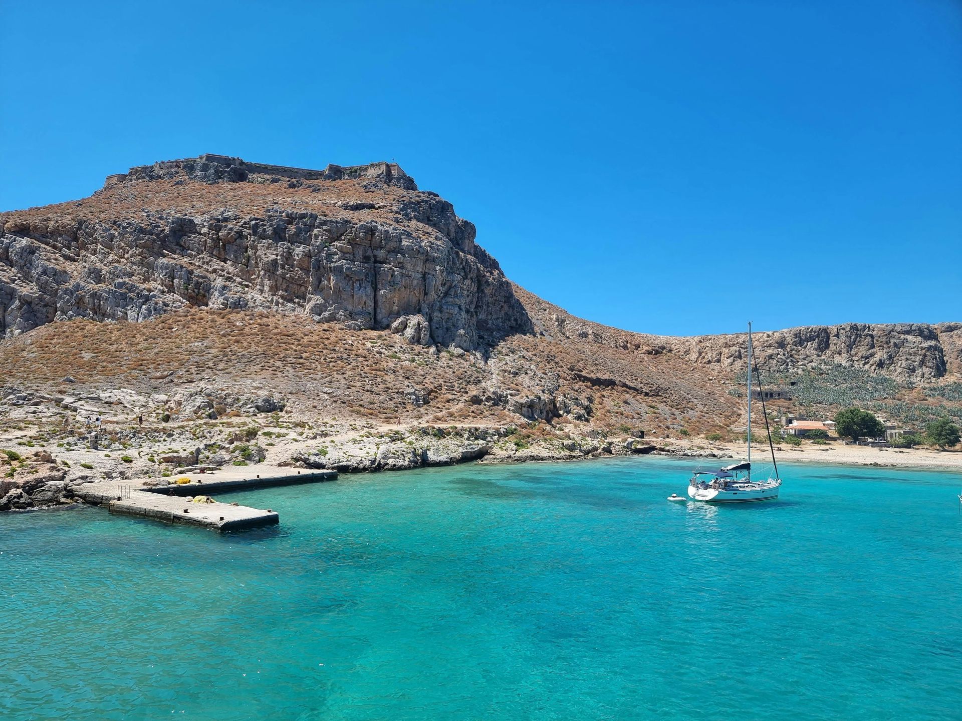 A boat is floating on top of a body of water with a mountain in the background in Crete, Greece.