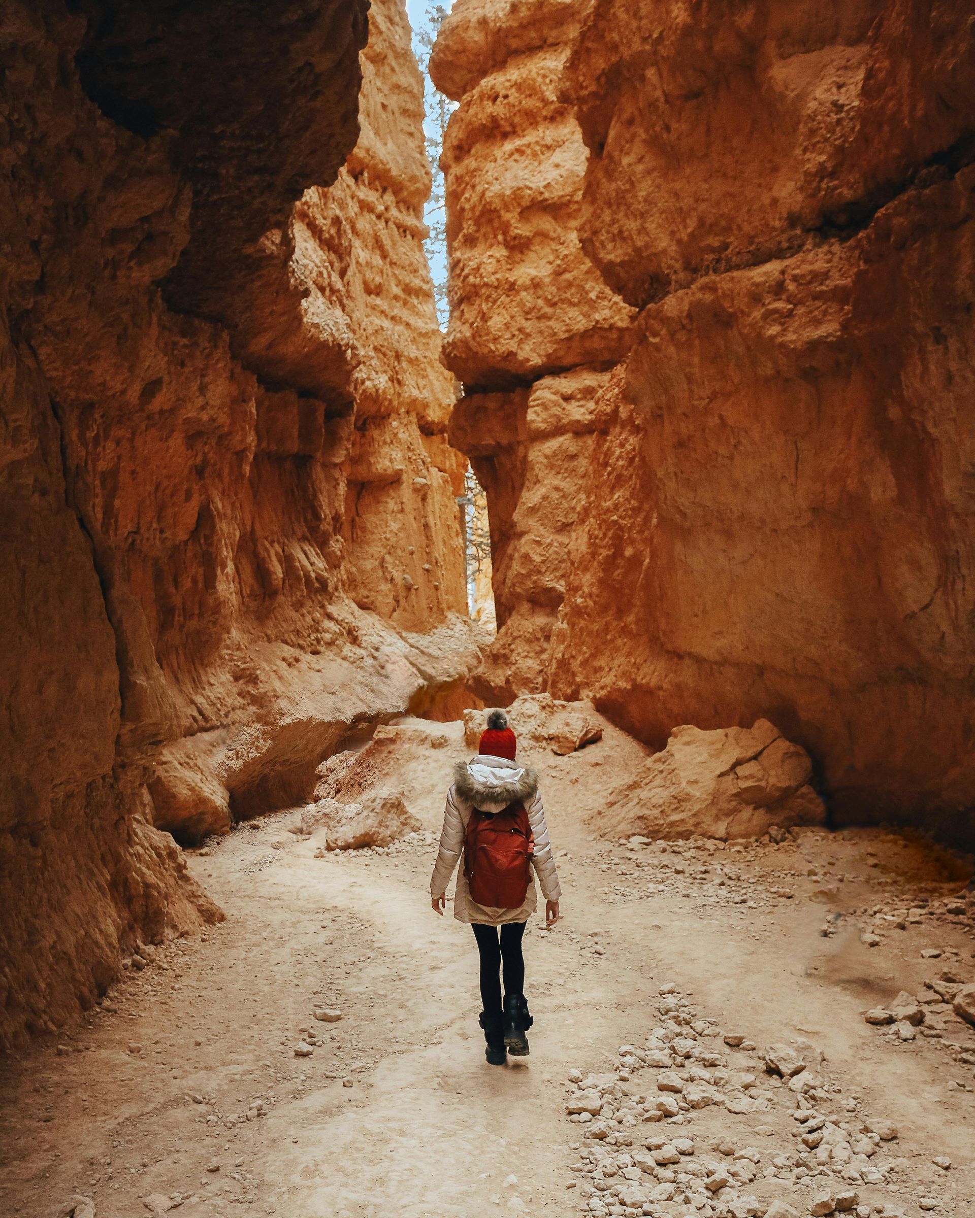 A person with a backpack is walking through a canyon at Bryce Canyon National Park in Utah.