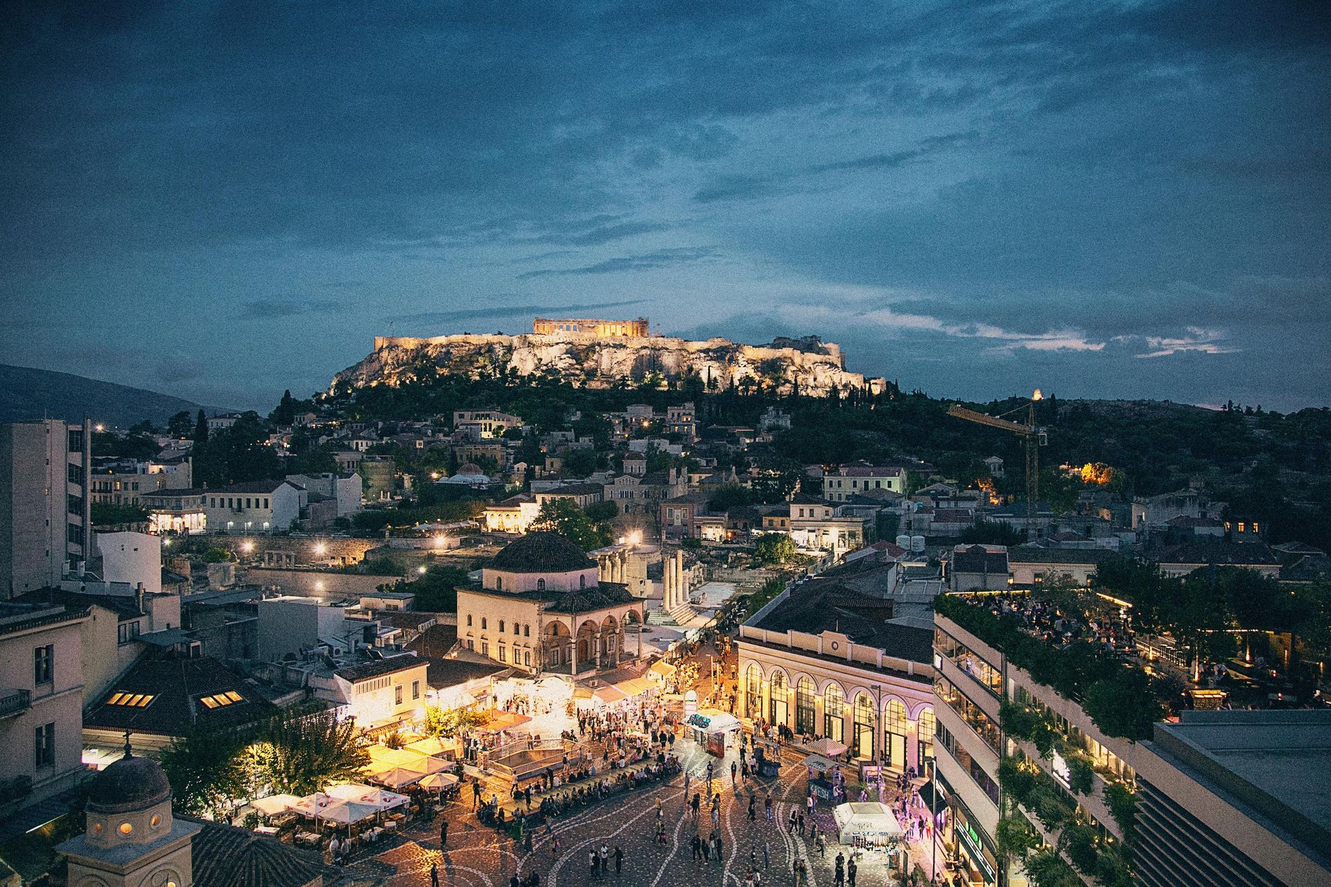 An aerial view of Athens, Greece at night with a temple in the background.