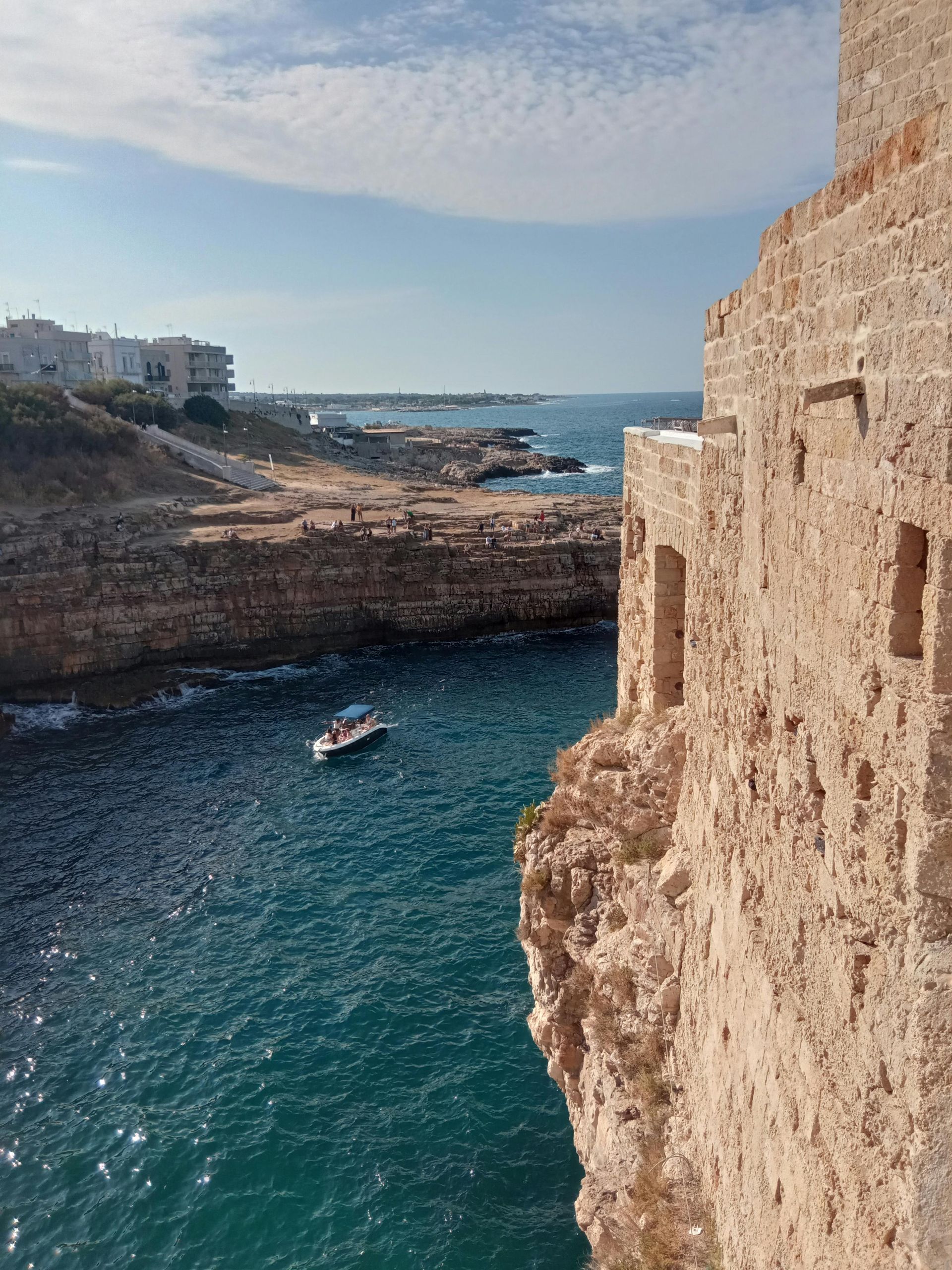 A boat is floating on top of a body of water next to Polignano a Mare in Puglia, Italy.