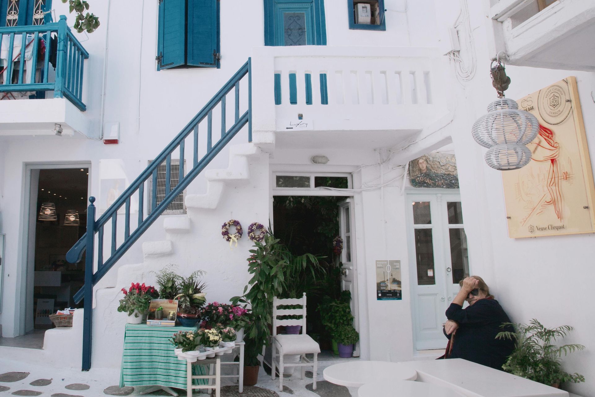 A white building with blue shutters and stairs in Mykonos, Greece.