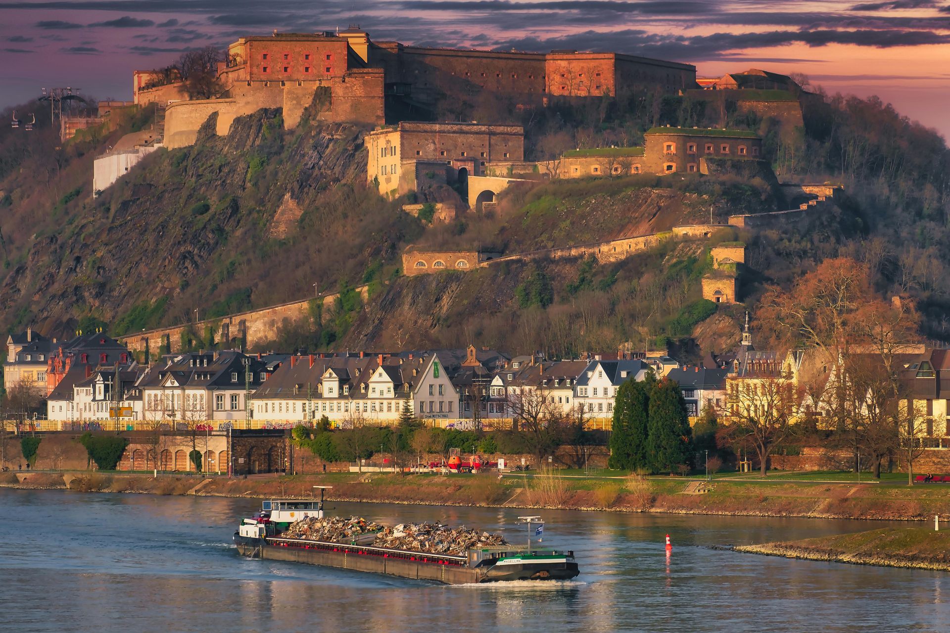 A boat is going down The Rhine River with a castle in the background.