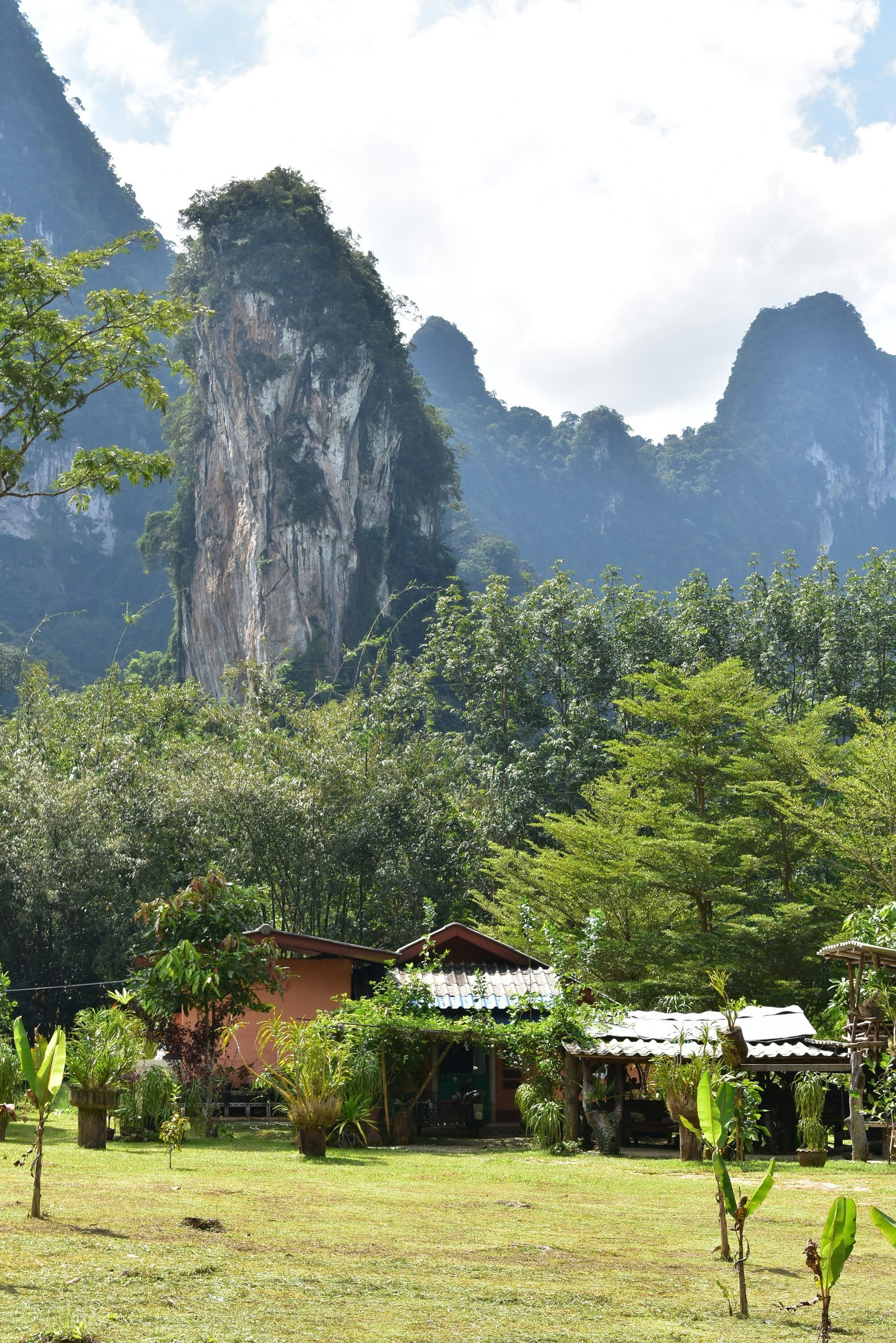 A house in the middle of a field with mountains in the background in Khao Sok National Park. Thailand.