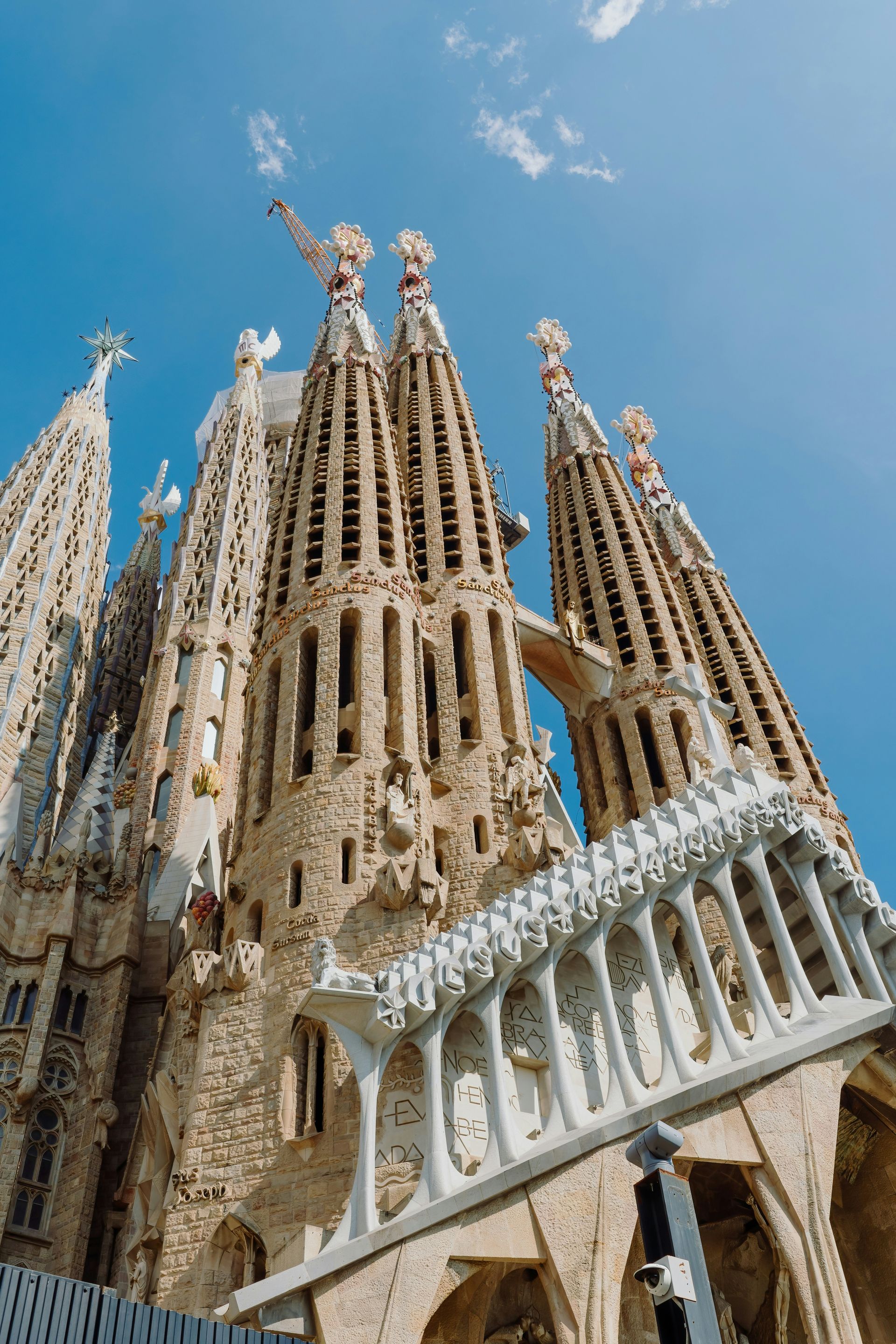 Sagrada Familia cathedral, Barcelona, Spain, against a bright blue sky; ornate, stone facade and towers.