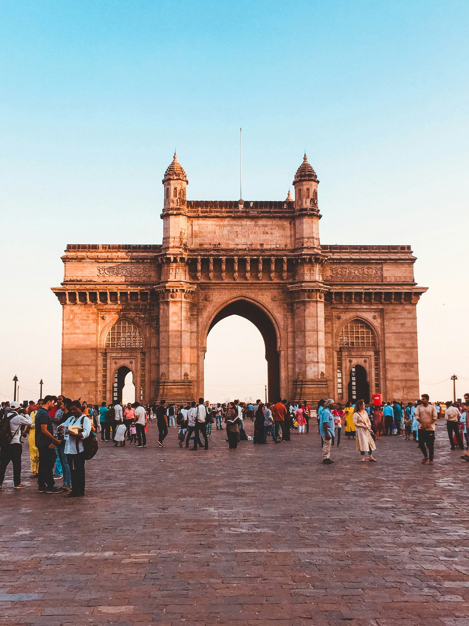 Gateway of India arch in Mumbai with people gathered in front.