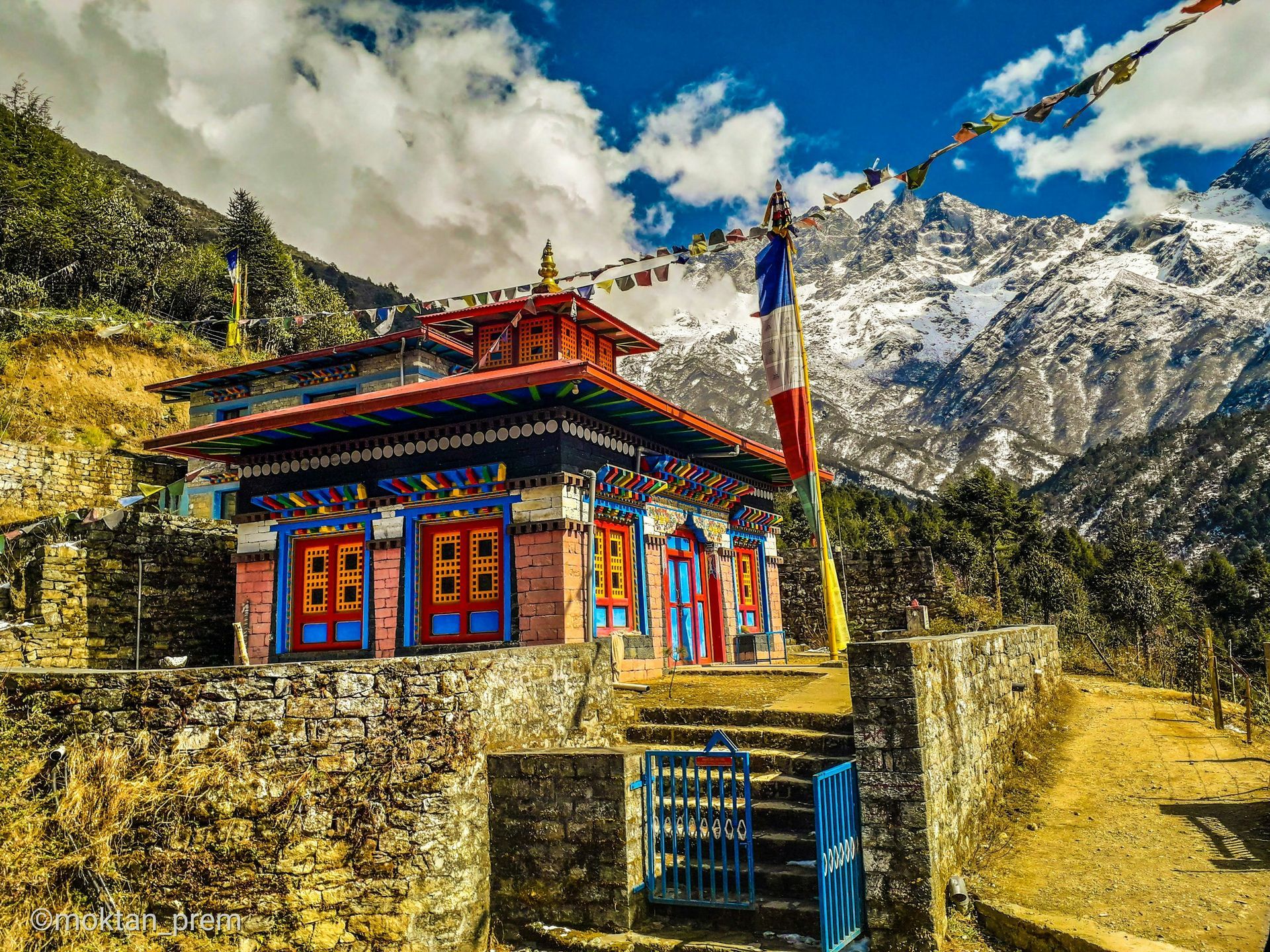 Colorful temple in the Himalayas with prayer flags; snow-capped mountains in Sagarmatha, Nepal.