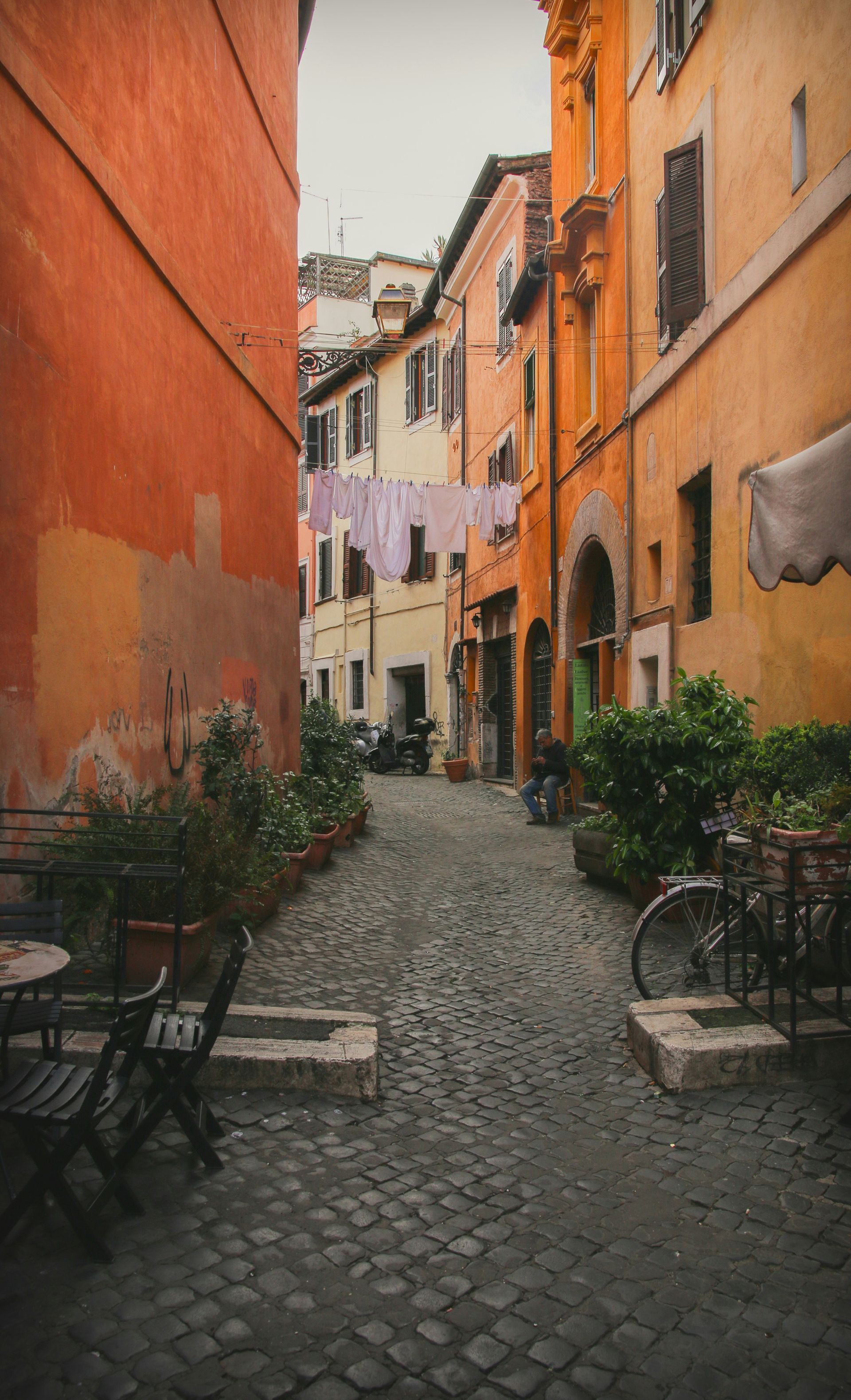 A narrow alleyway between two buildings with a bicycle parked in the middle in Rome.