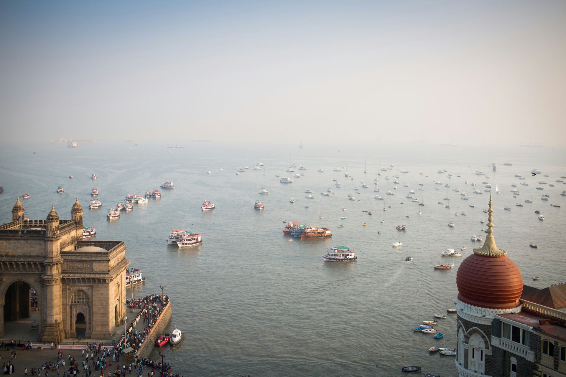 Gateway of India and Taj Mahal Palace Hotel overlooking the Arabian Sea, filled with boats, Mumbai.