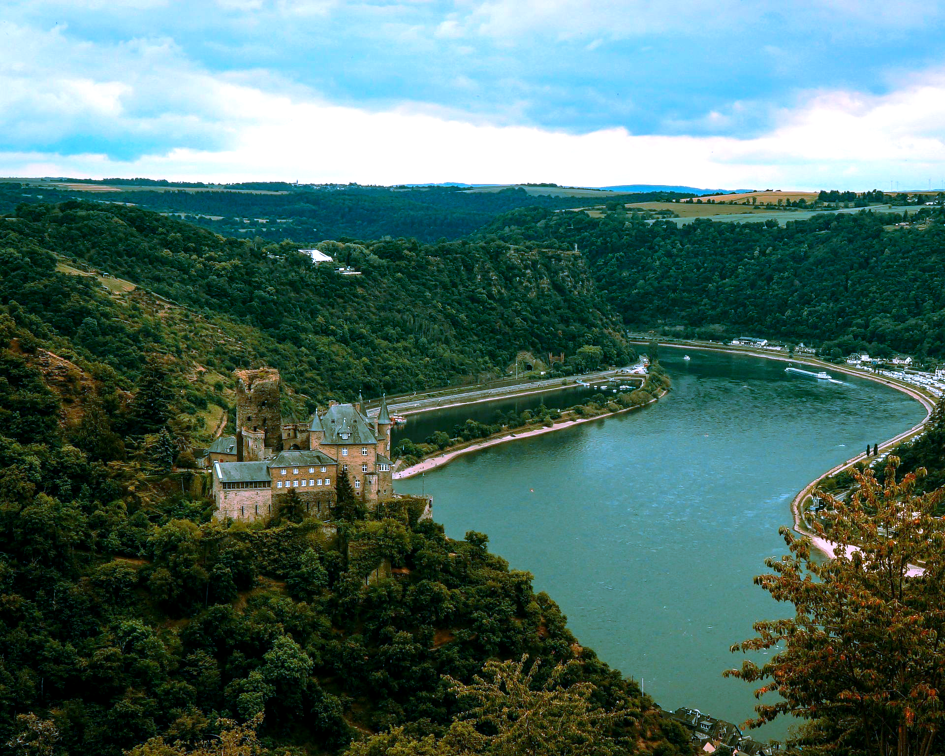 Burg Katz Castle on a riverbank surrounded by green hills and forest in Sankt Goarshausen, Germany.